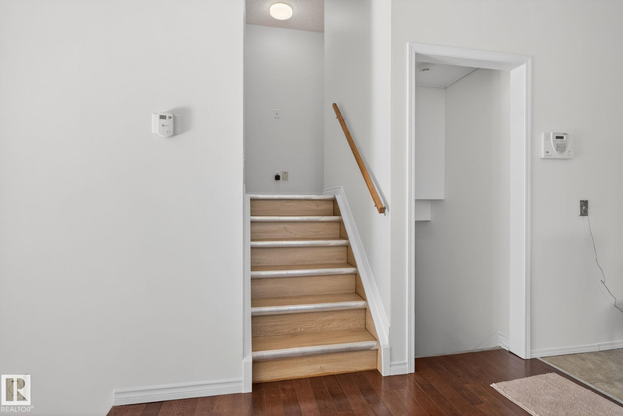 Staircase with light wood treads and a natural wood handrail - 8403 190 Street, Edmonton, AB - Indoor Photo Showing Other Room