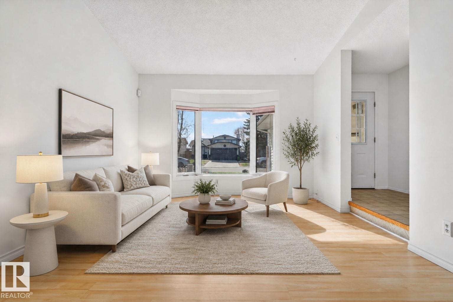Bright living space featuring a large bay window, light wood-finish flooring, and white painted walls - 8403 190 Street, Edmonton, AB - Indoor Photo Showing Living Room