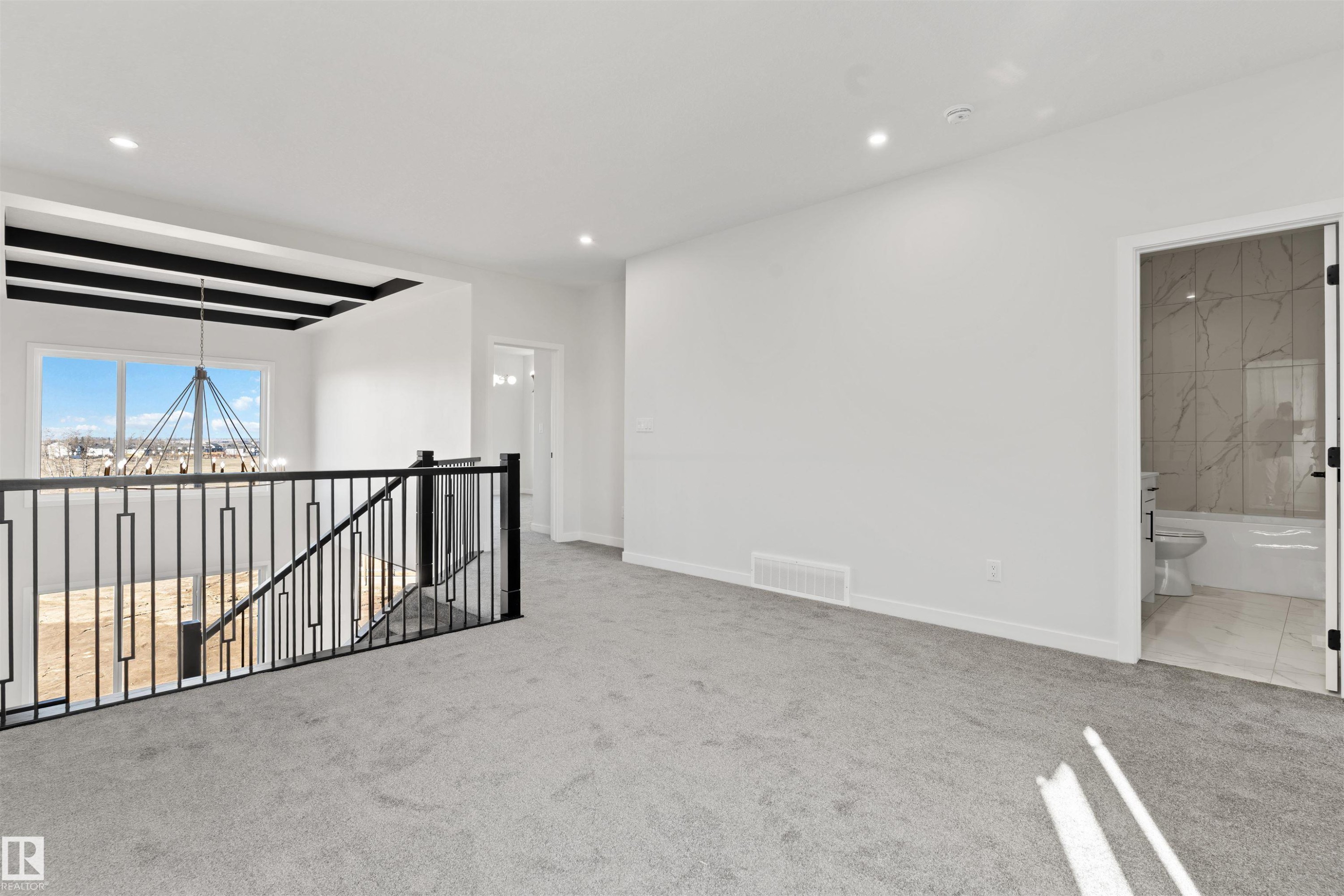Carpeted upper-level landing with wrought iron railing, recessed lighting, and a chandelier - 1849 Crossbill Loop Nw, Edmonton, AB - Indoor Photo Showing Other Room