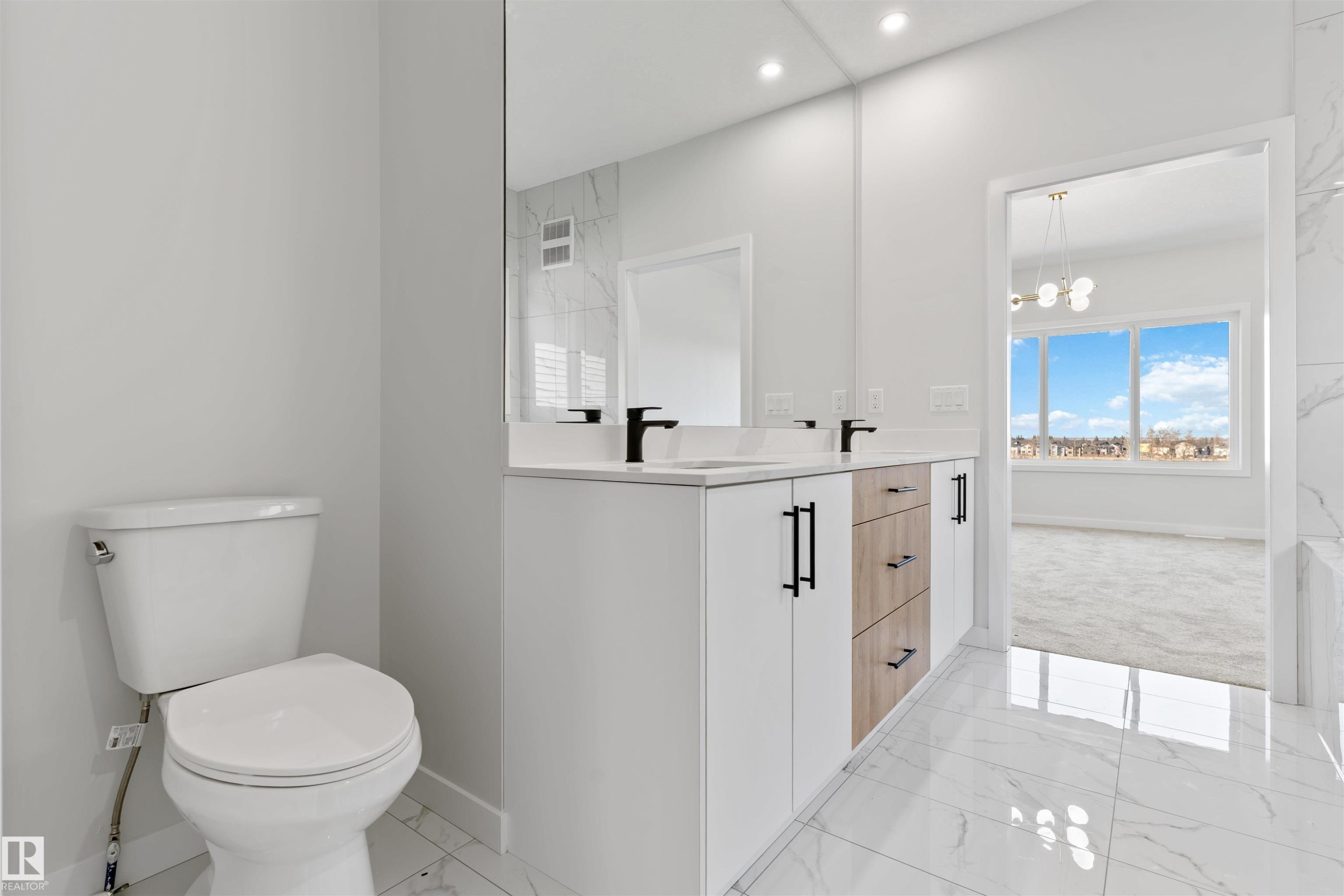 Bathroom featuring a dual vanity with white cabinetry, wood-finish drawers, and matte black hardware - 1849 Crossbill Loop Nw, Edmonton, AB - Indoor Photo Showing Bathroom