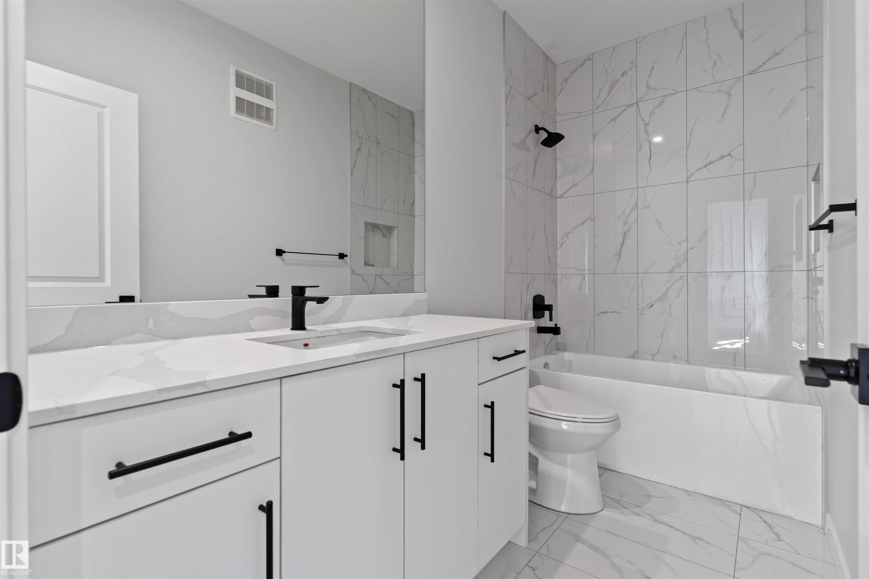 Contemporary bathroom featuring a spacious vanity with an undermount sink, a large mirror, a tiled shower with a built-in niche, and matte black hardware - 1849 Crossbill Loop Nw, Edmonton, AB - Indoor Photo Showing Bathroom