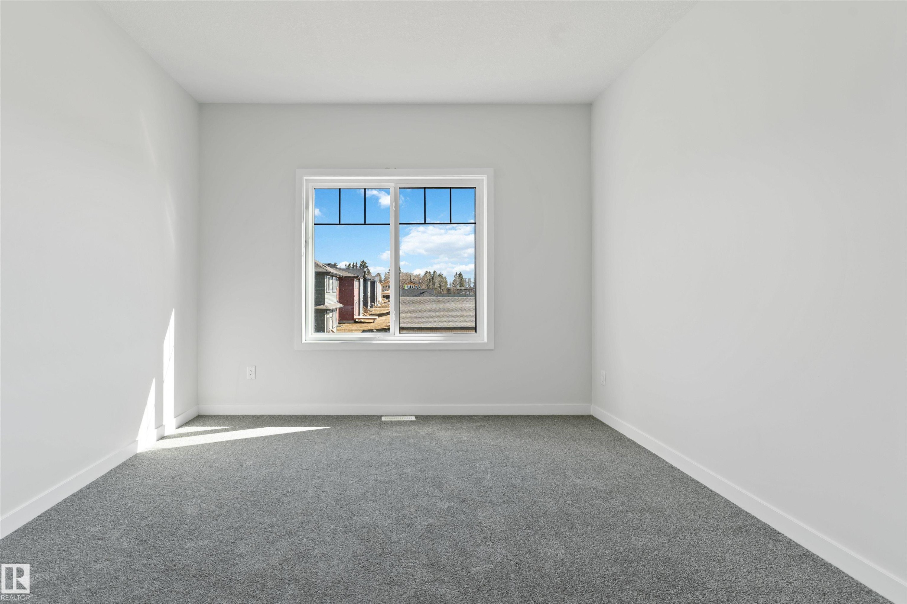 Bright room featuring a large window, neutral gray carpeting, white walls, white trim, and a white ceiling - 1849 Crossbill Loop Nw, Edmonton, AB - Indoor Photo Showing Other Room