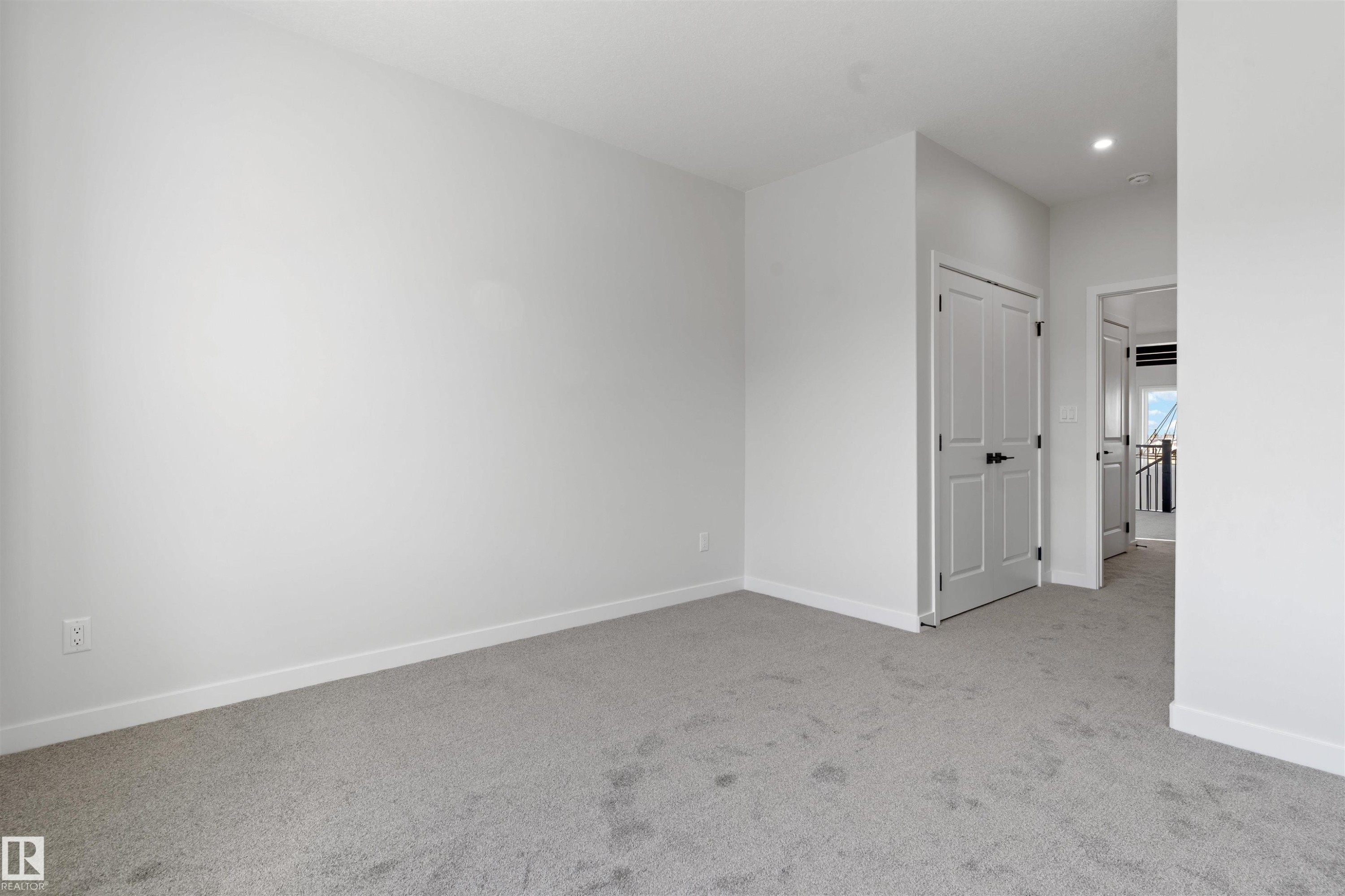 Carpeted room with light gray walls, white trim, and a white paneled door with black hardware - 1849 Crossbill Loop Nw, Edmonton, AB - Indoor Photo Showing Other Room