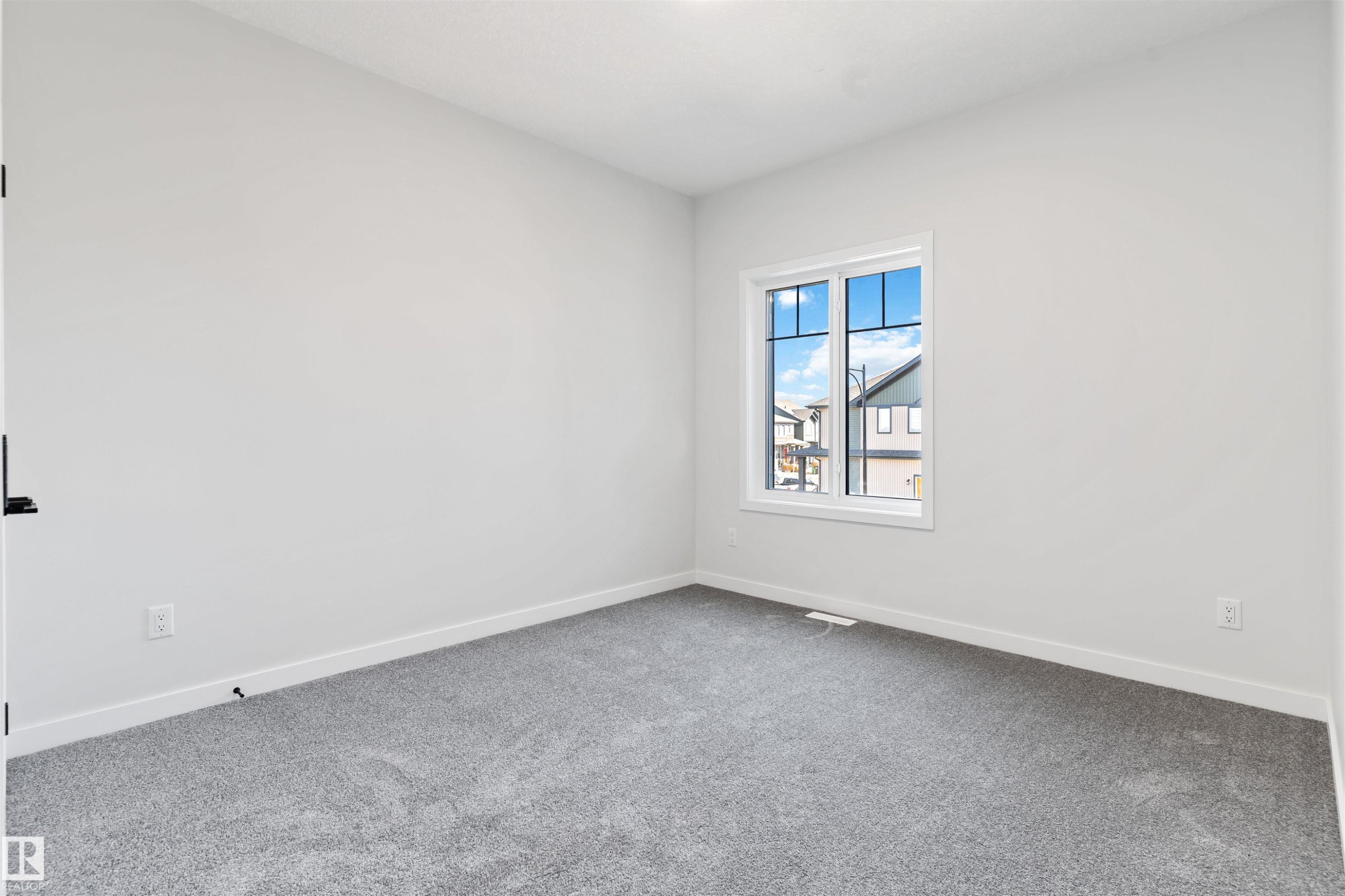 Neutral tone walls with white trim, gray plush carpeting, and a white-framed window - 1849 Crossbill Loop Nw, Edmonton, AB - Indoor Photo Showing Other Room