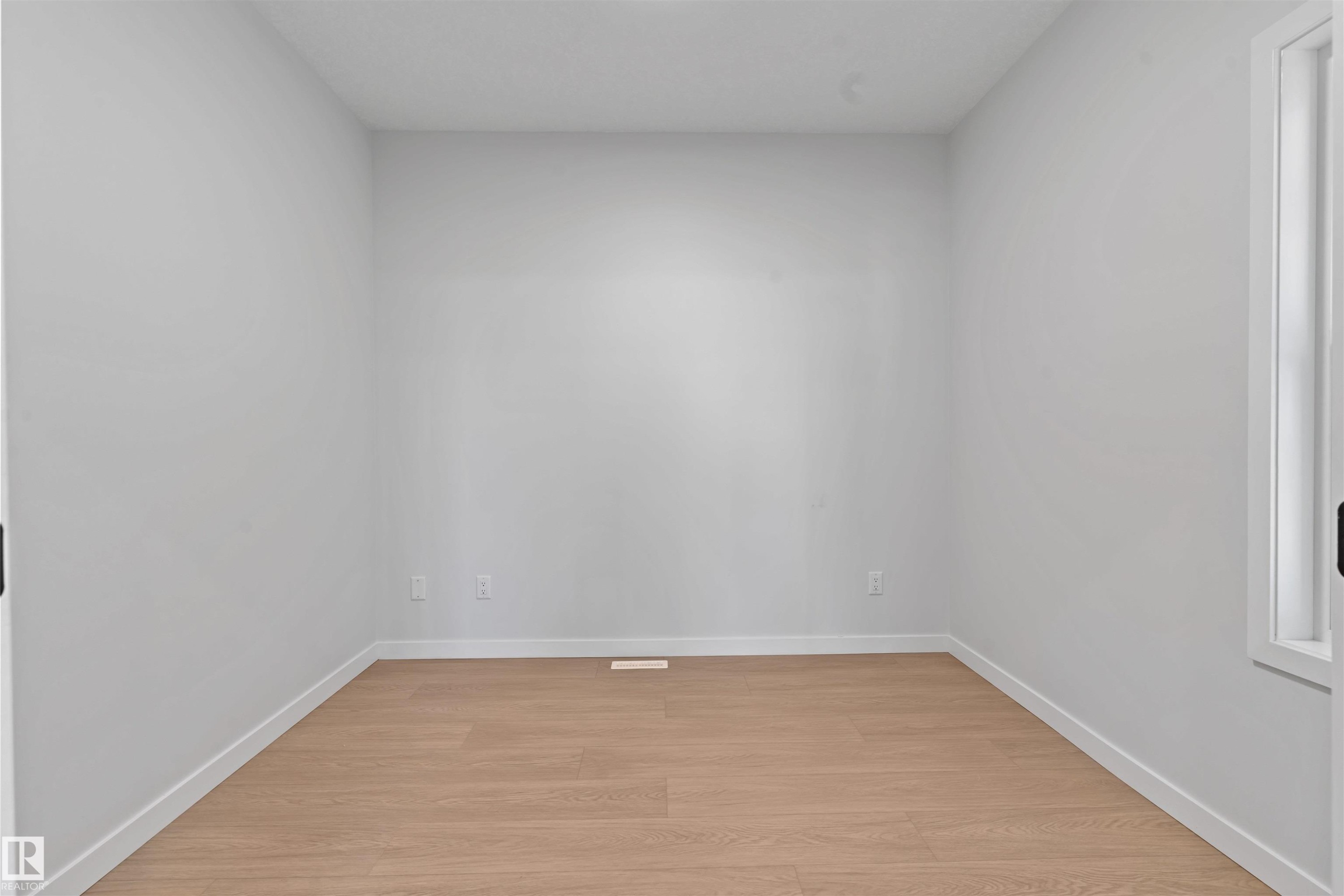 Light wood-finish flooring complements the neutral wall color in this room featuring a window with white trim - 1849 Crossbill Loop Nw, Edmonton, AB - Indoor Photo Showing Other Room