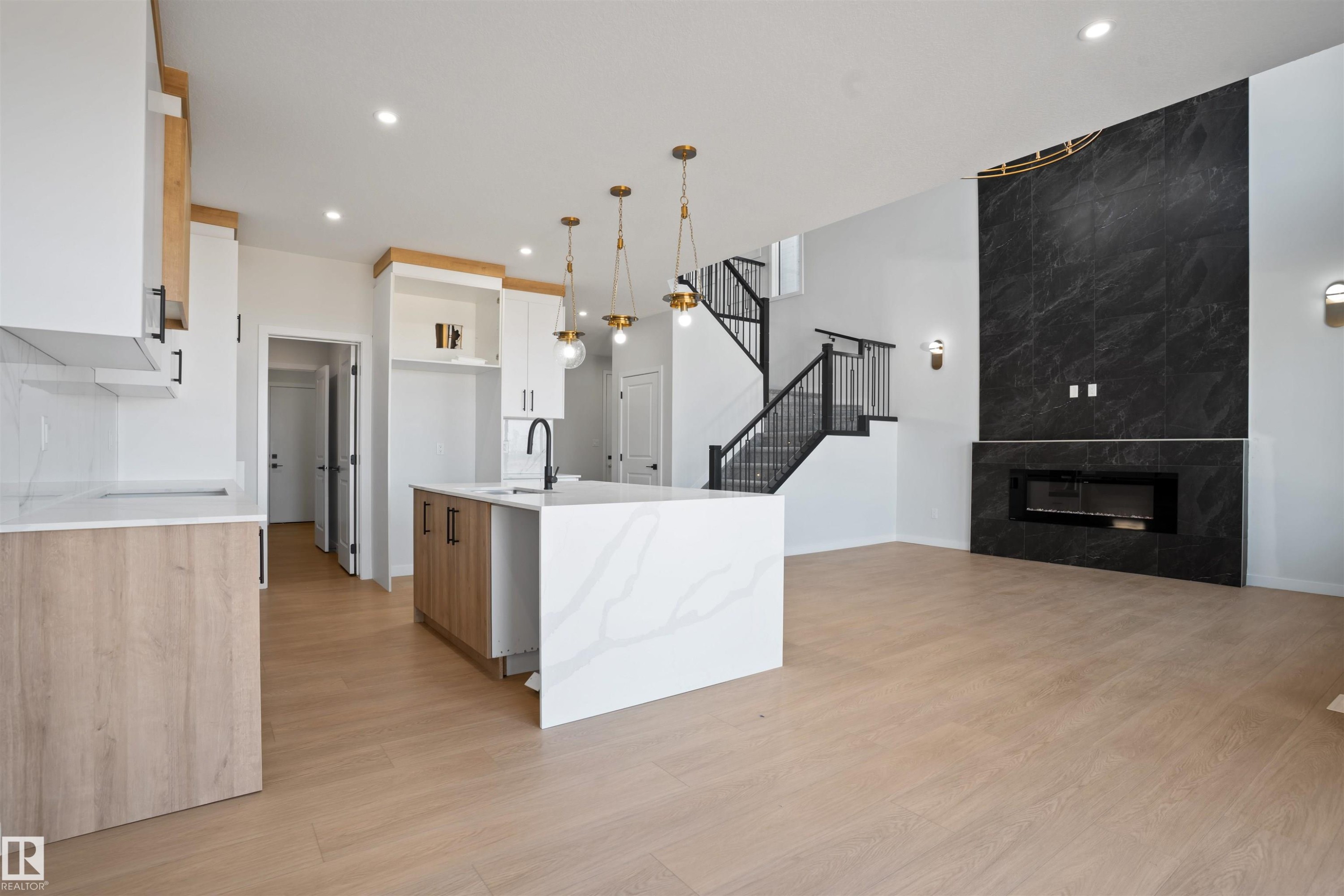 Open-concept living space featuring light wood-finish flooring - 1849 Crossbill Loop Nw, Edmonton, AB - Indoor With Fireplace