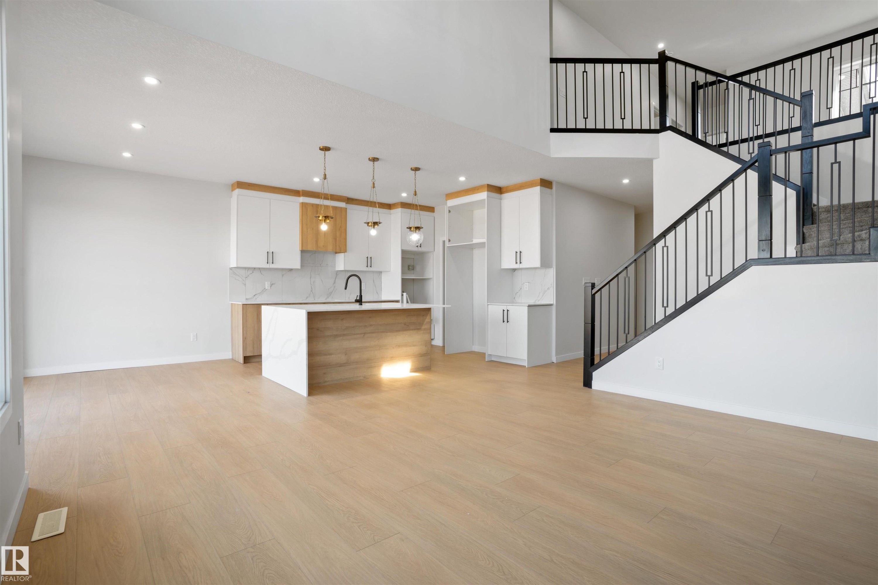 Open-concept living area featuring light wood-finish flooring, recessed lighting, and a modern kitchen - 1849 Crossbill Loop Nw, Edmonton, AB - Indoor Photo Showing Kitchen