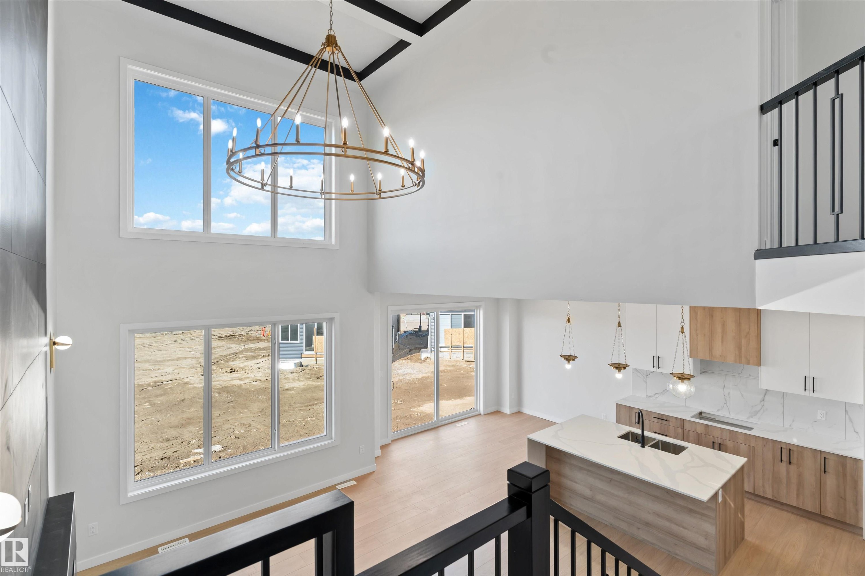 Two-story living area with a contemporary chandelier, large windows, and wood-finish flooring - 1849 Crossbill Loop Nw, Edmonton, AB - Indoor Photo Showing Kitchen