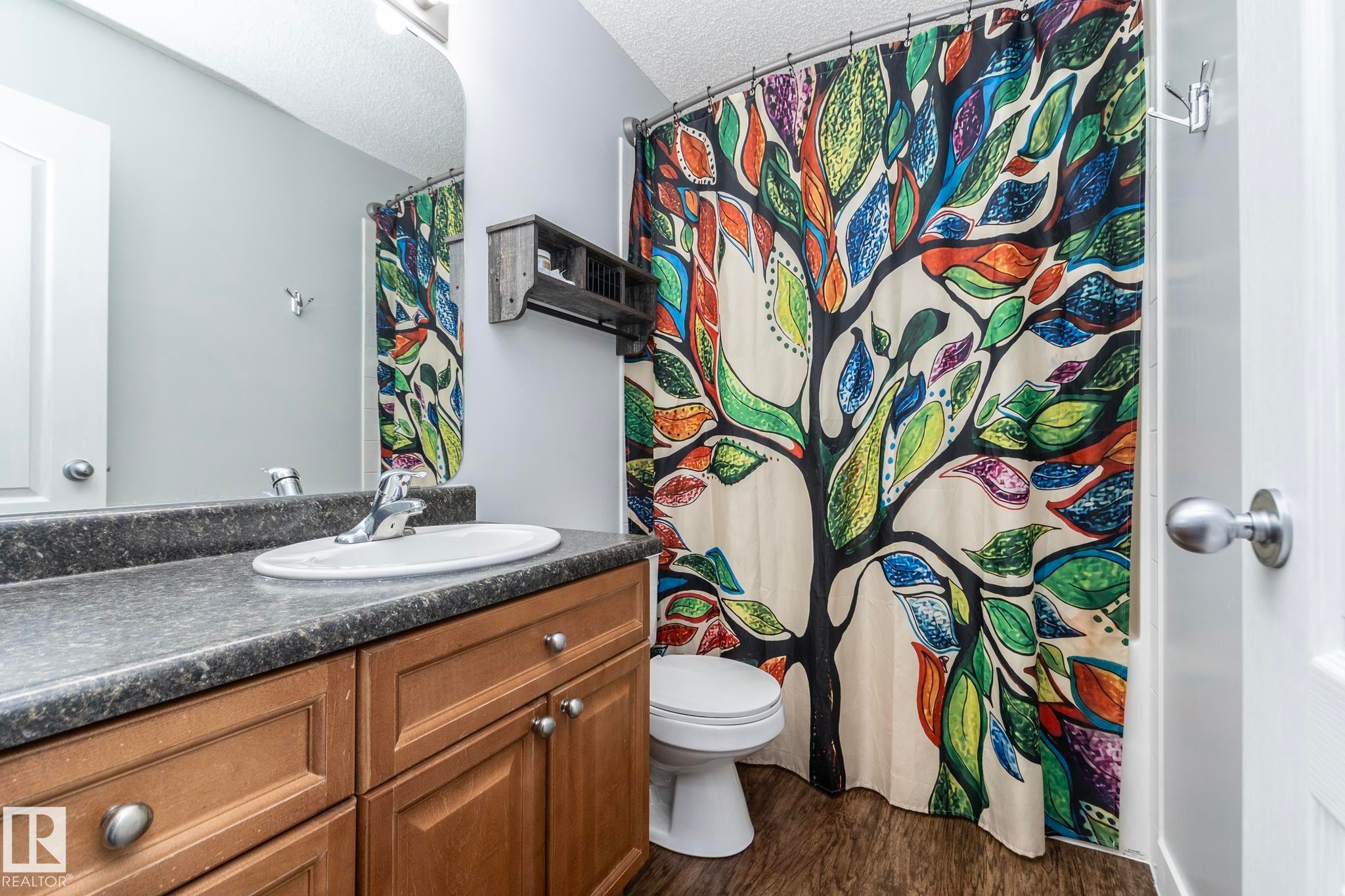 Bathroom featuring a wood-finish vanity with an integrated sink and laminate countertop - 65 Birchmont Drive, Leduc, AB - Indoor Photo Showing Bathroom