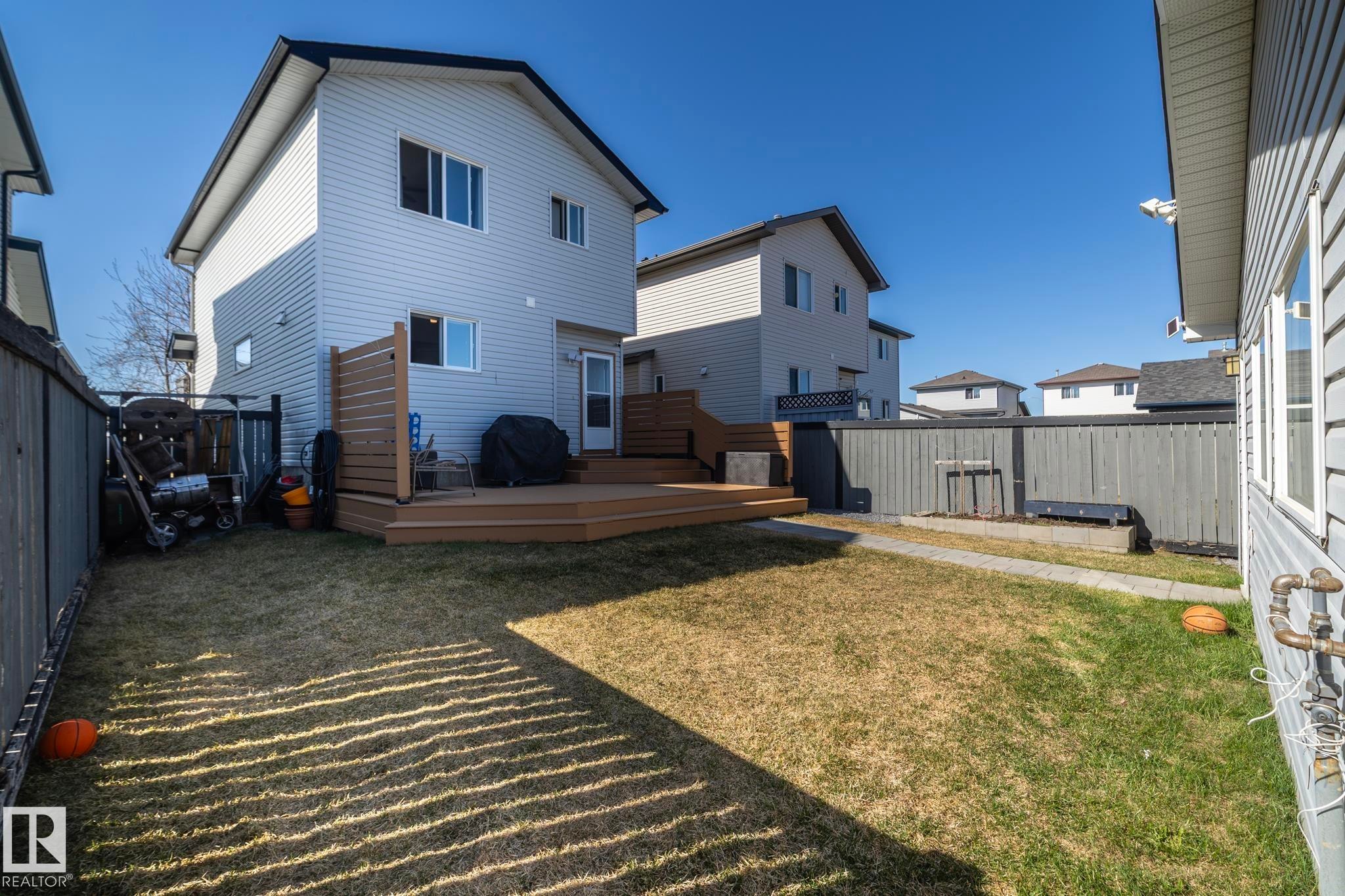 Expansive backyard featuring a multi-level wood-tone deck with a privacy screen - 65 Birchmont Drive, Leduc, AB - Outdoor With Exterior