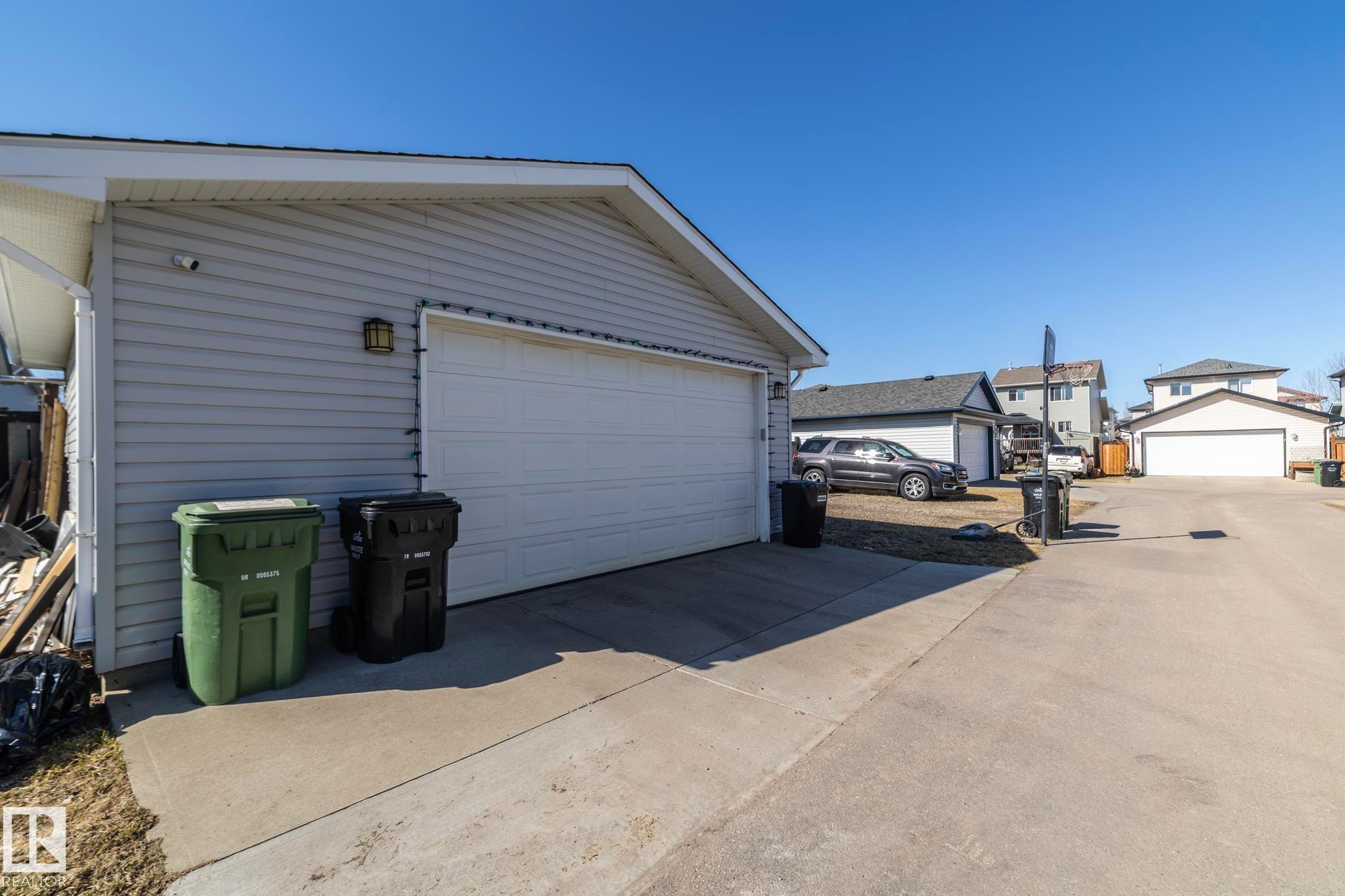 Detached garage featuring light-colored siding and a white overhead door - 65 Birchmont Drive, Leduc, AB - Outdoor With Exterior