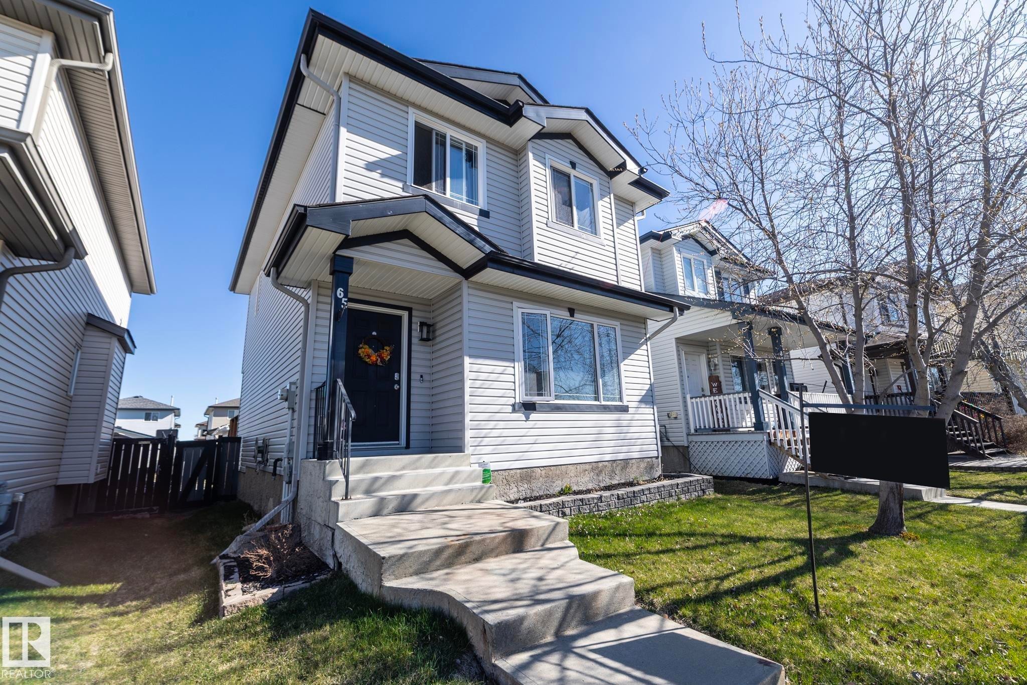 Two-story residence featuring light-colored siding and a contrasting dark roofline - 65 Birchmont Drive, Leduc, AB - Outdoor