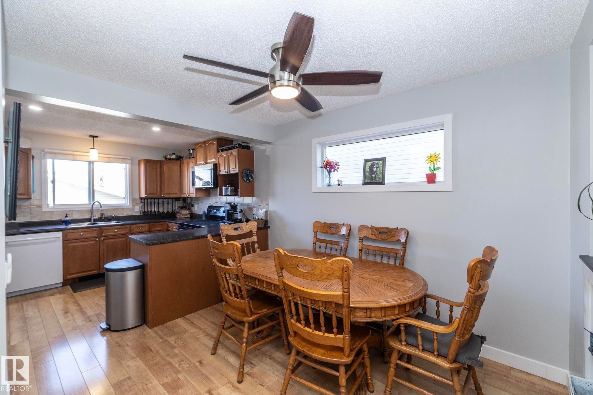Kitchen and dining area featuring wood-finish flooring - 65 Birchmont Drive, Leduc, AB - Indoor