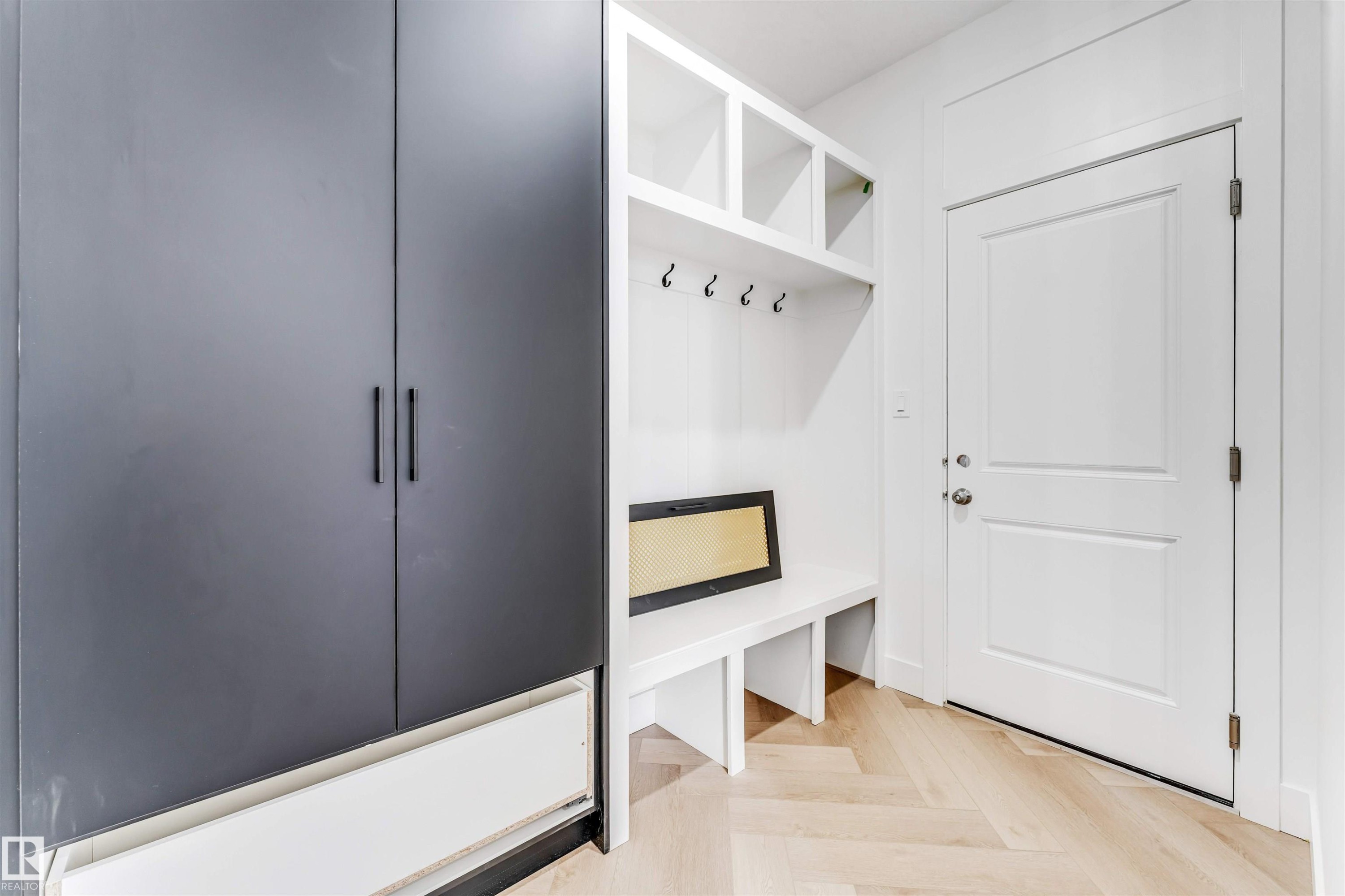 Entryway featuring light wood-finish herringbone flooring and a built-in mudroom bench with cubbies and coat hooks - 4006 35 St, Beaumont, AB - Indoor Photo Showing Other Room