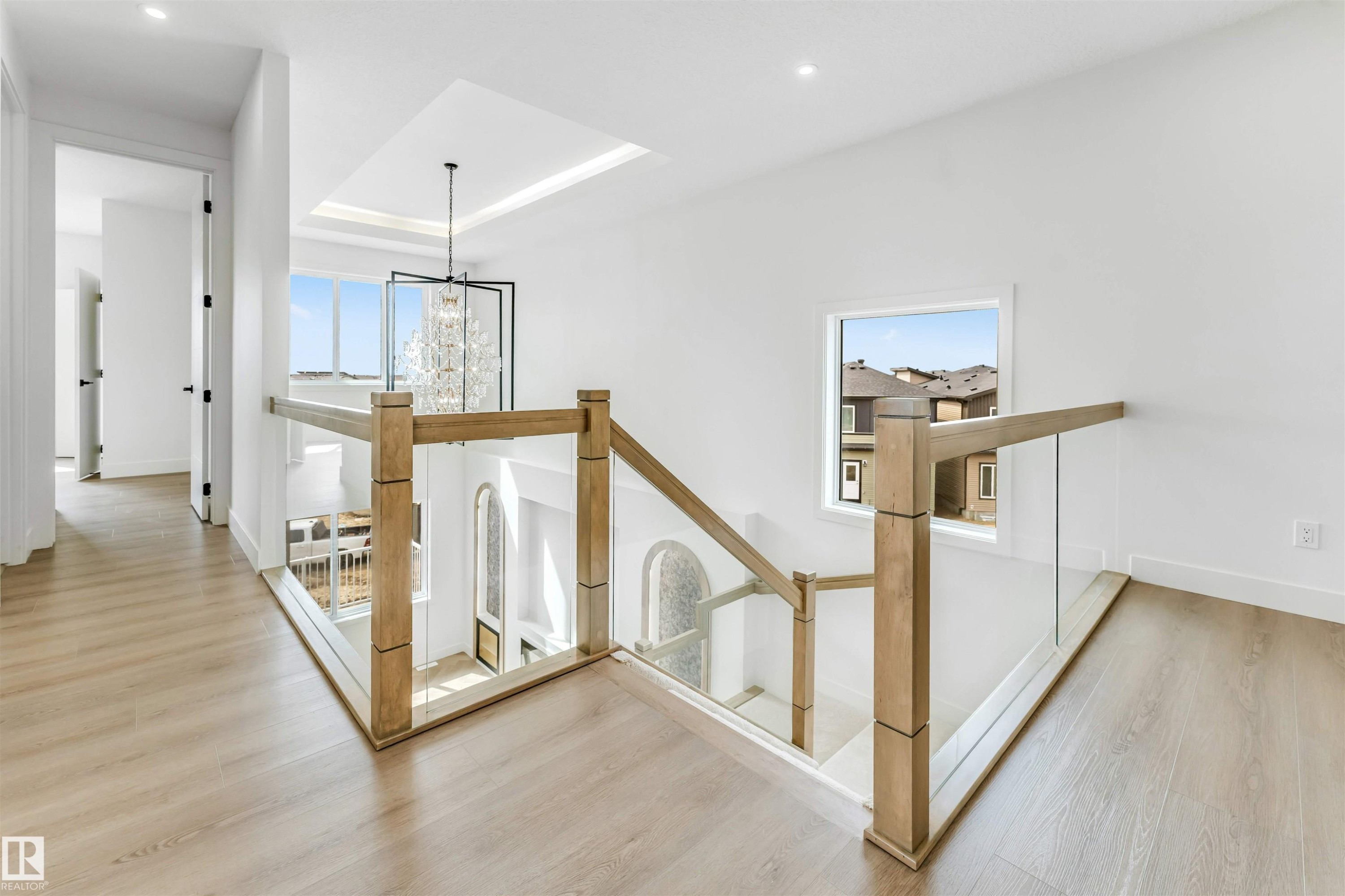 Upper-level hallway featuring wood-finish flooring, recessed lighting, and a contemporary glass and wood railing system - 4006 35 St, Beaumont, AB - Indoor Photo Showing Other Room