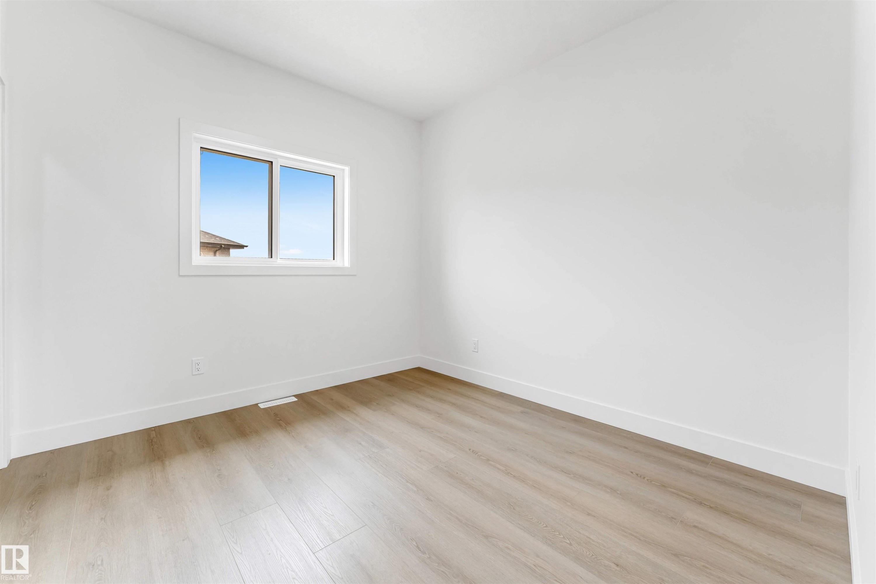 Room featuring a large window, light wood-finish flooring, white walls, white baseboards, and white window trim - 4006 35 St, Beaumont, AB - Indoor Photo Showing Other Room