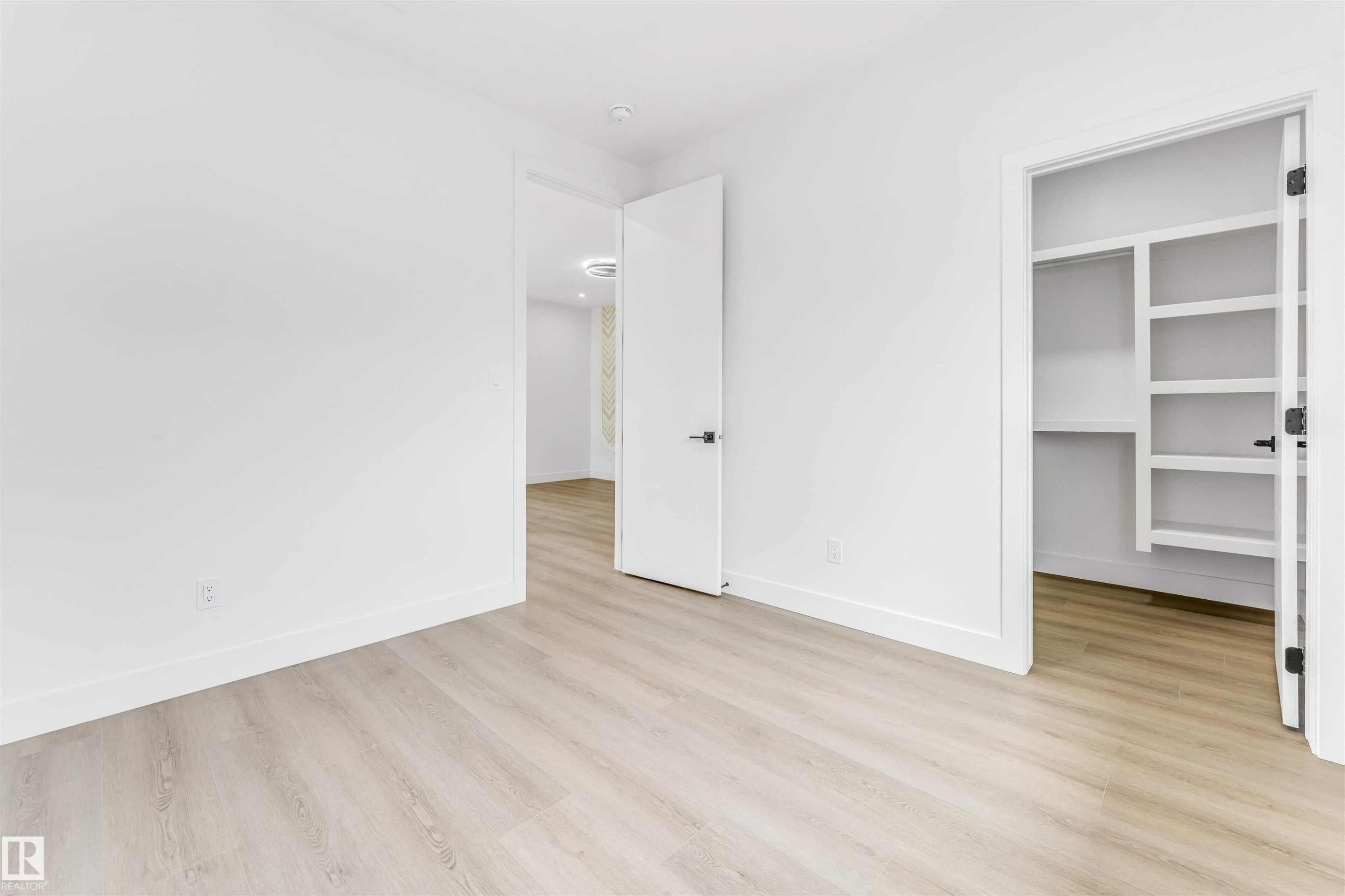 Bright interior space with light wood-finish flooring, white walls, and a built-in closet system - 4006 35 St, Beaumont, AB - Indoor Photo Showing Other Room