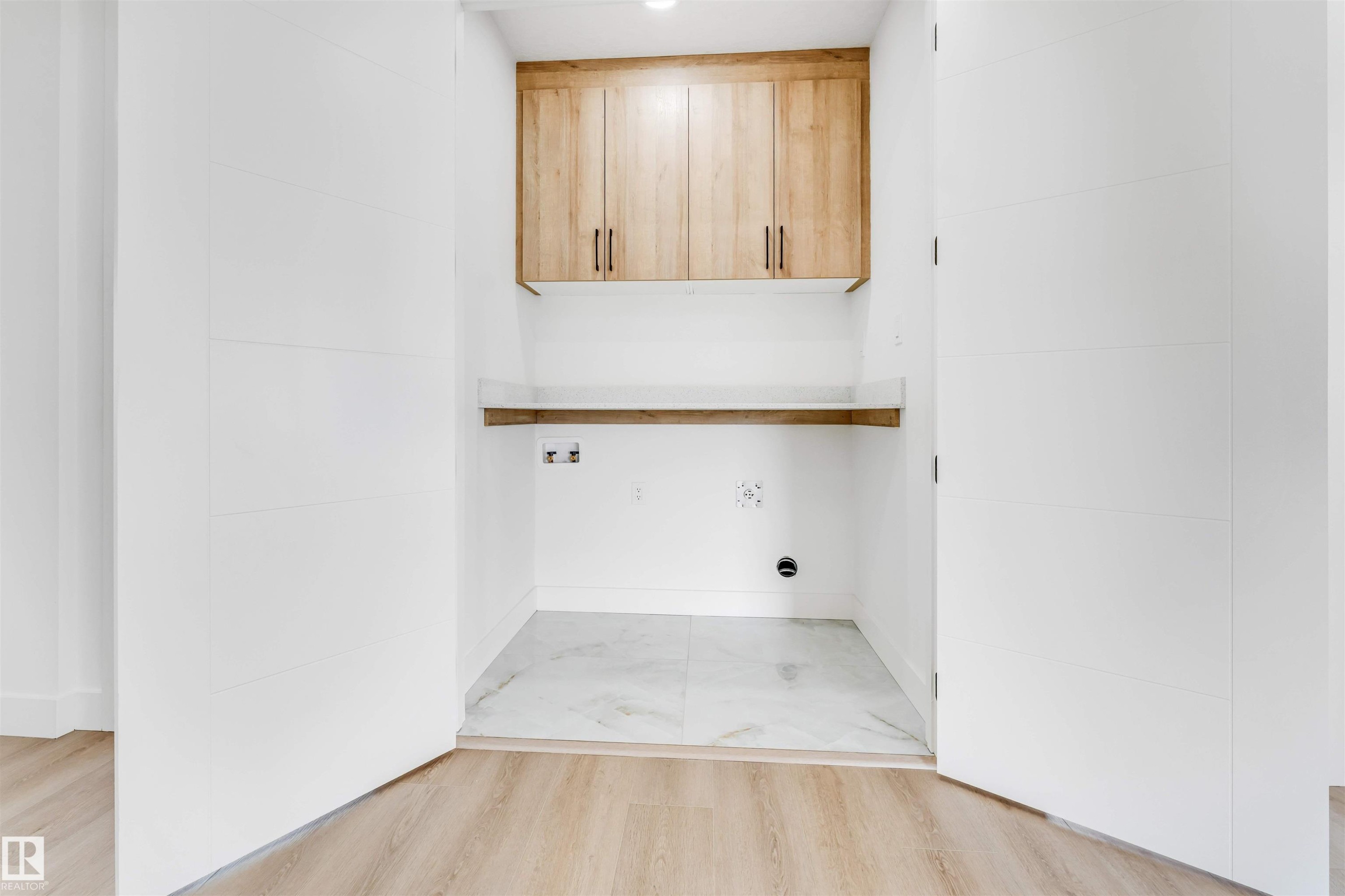 Laundry area featuring light wood-finish cabinetry with dark hardware, a wood-finish shelf, and a light-toned countertop - 4006 35 St, Beaumont, AB - Indoor Photo Showing Other Room