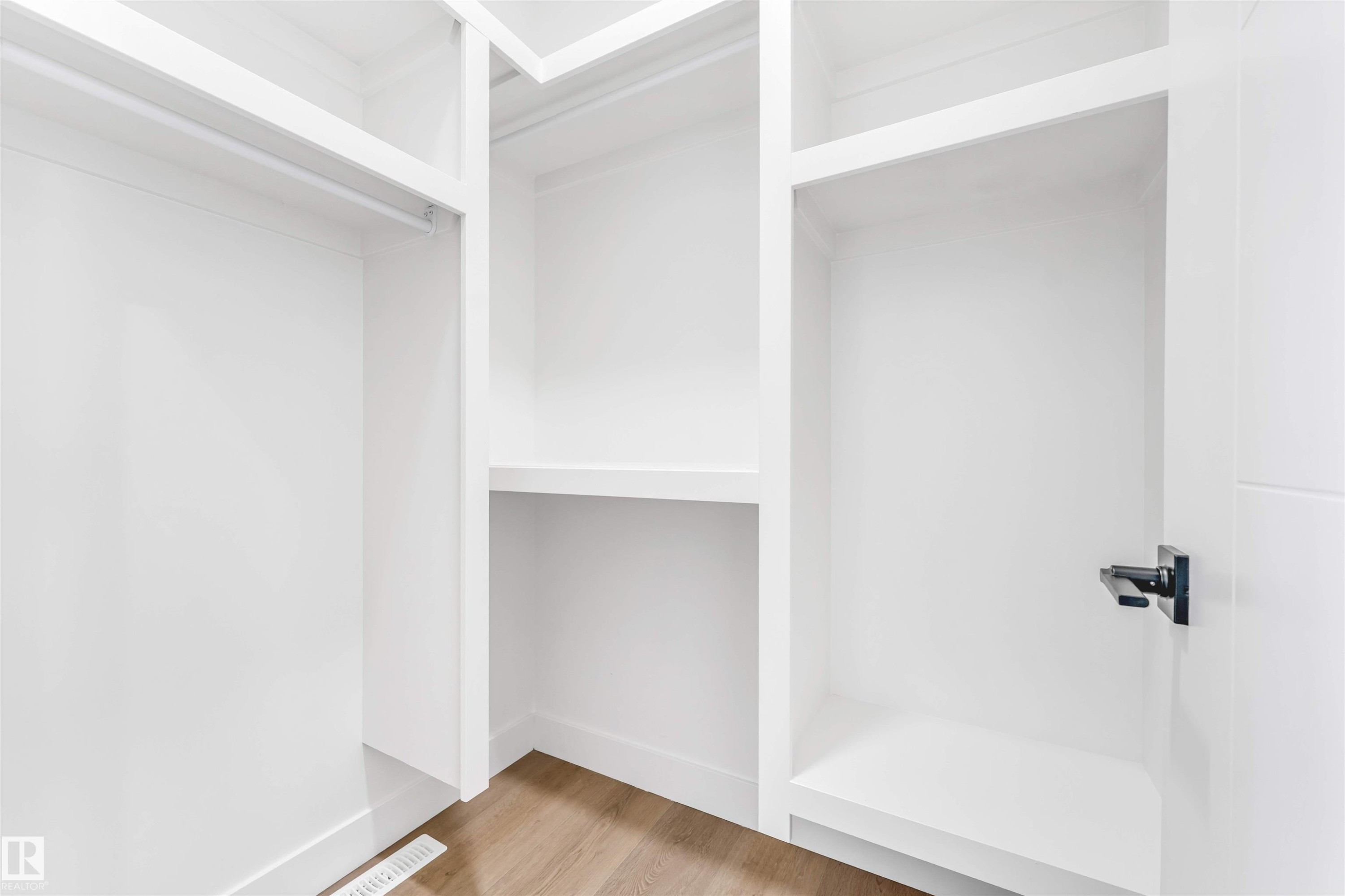Custom closet system featuring white shelving, hanging rod, and wood-finish flooring - 4006 35 St, Beaumont, AB - Indoor