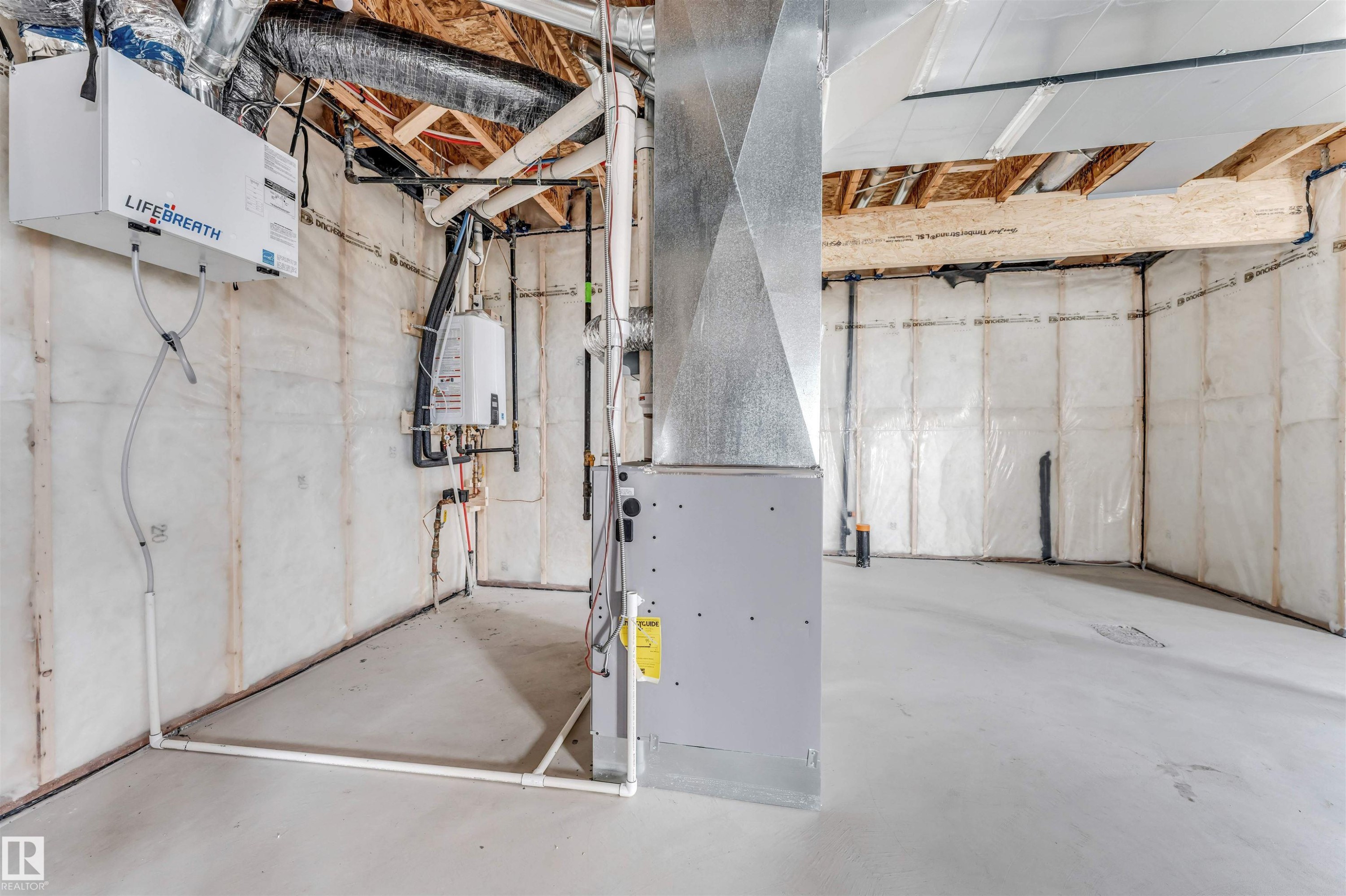 Unfinished basement featuring exposed wood joists, a concrete floor, installed insulation, an HVAC system, and a wall-mounted water heater - 4006 35 St, Beaumont, AB - Indoor Photo Showing Basement