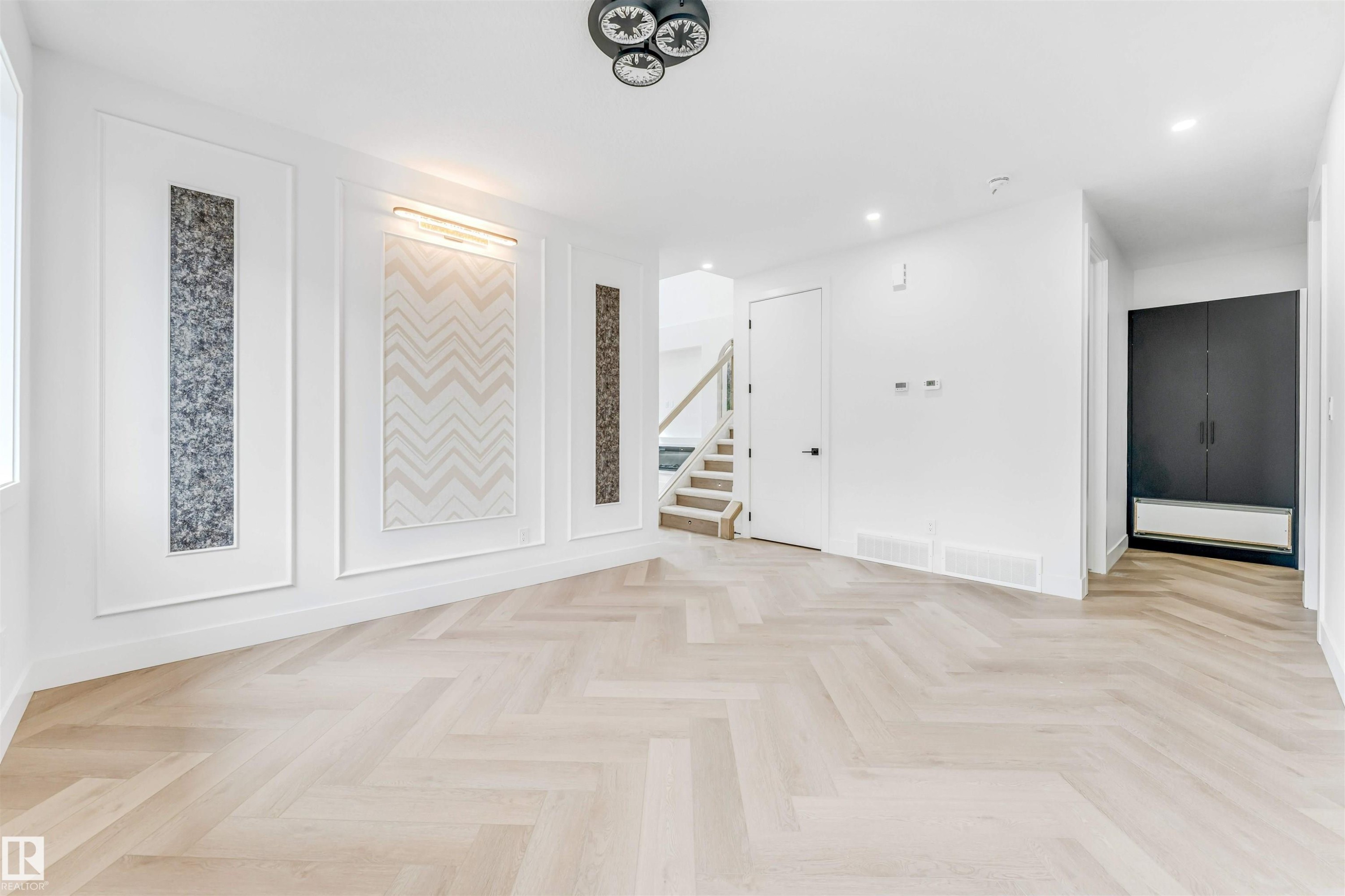 Open living space featuring herringbone-patterned wood-finish flooring - 4006 35 St, Beaumont, AB - Indoor Photo Showing Other Room