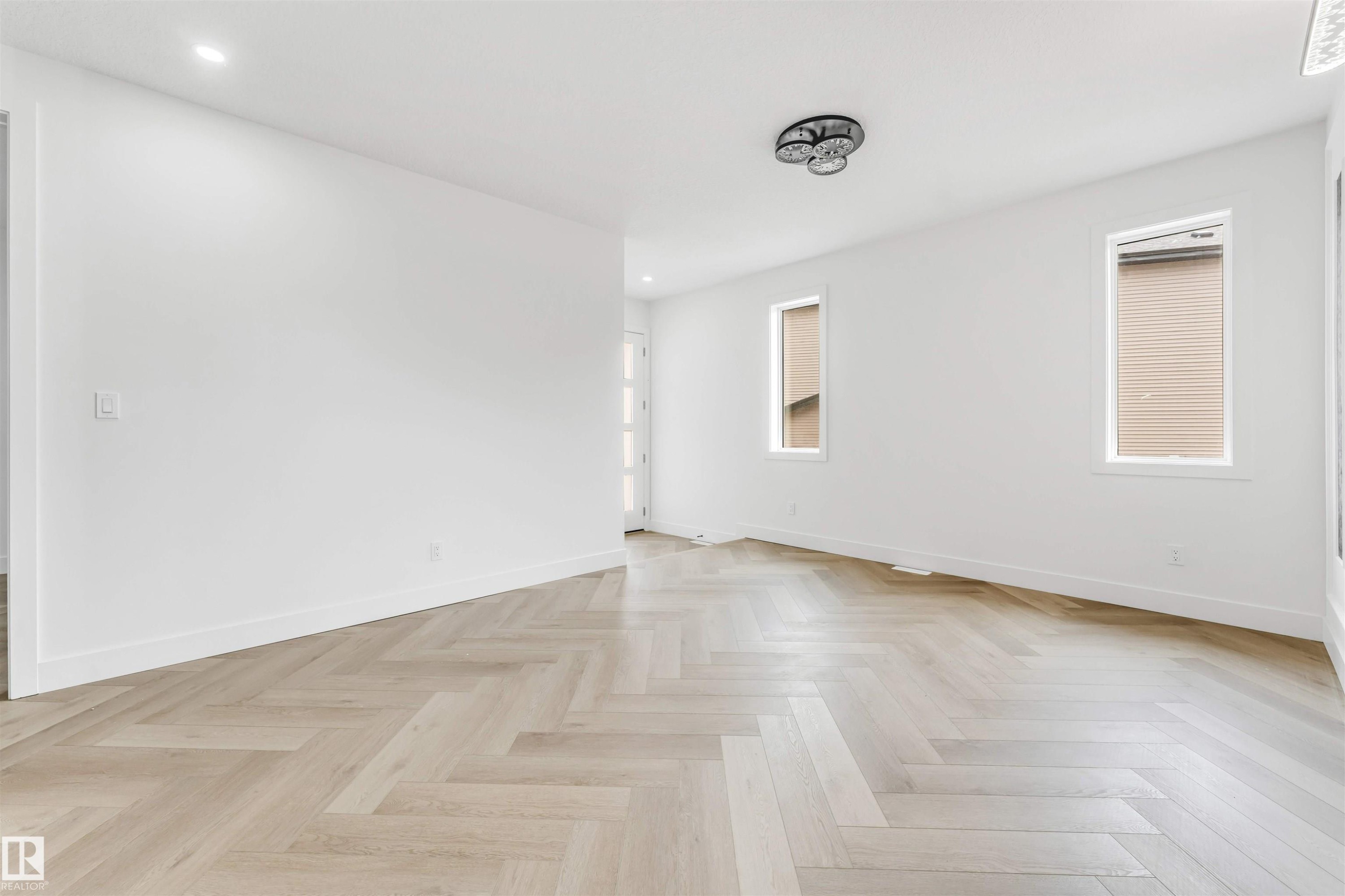 Herringbone wood-finish flooring complements the bright white walls - 4006 35 St, Beaumont, AB - Indoor Photo Showing Other Room