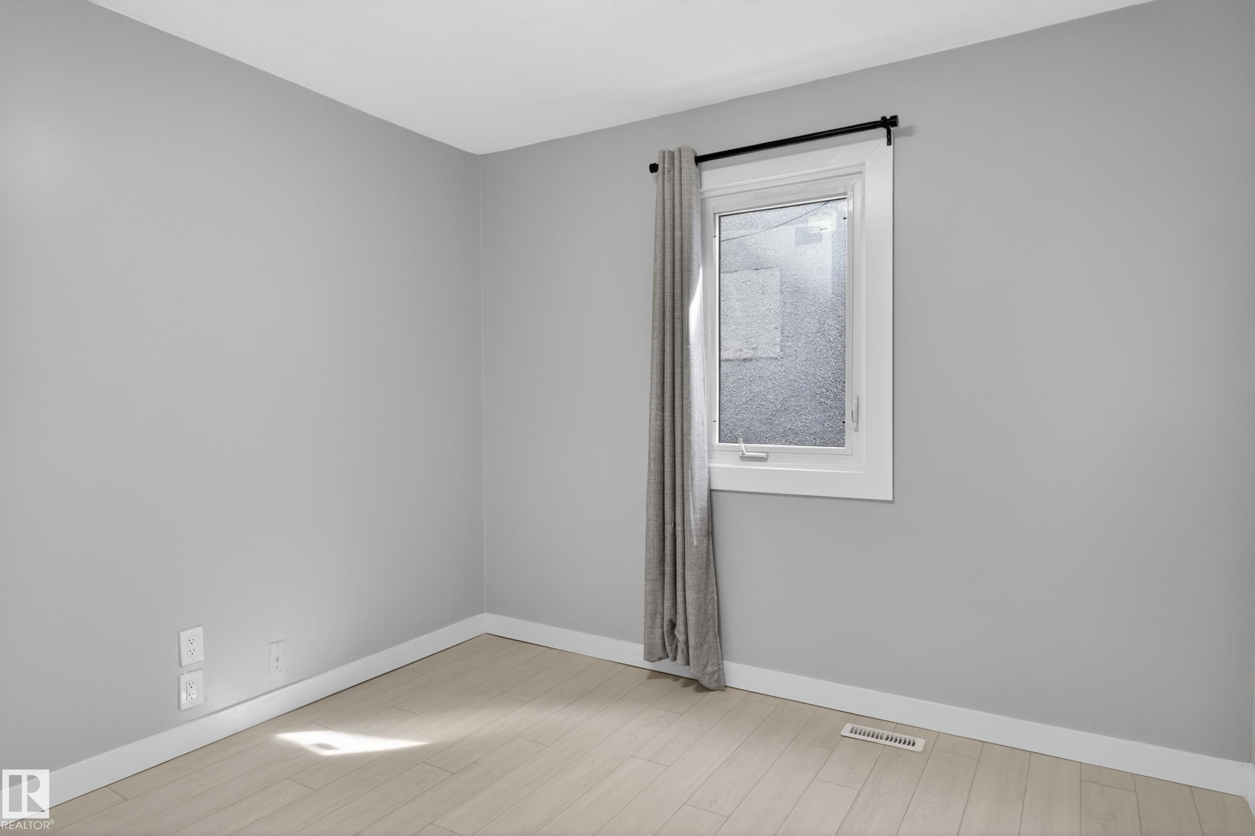 Neutral gray painted walls with white trim and light wood-finish flooring - 8722 112 Avenue, Edmonton, AB - Indoor Photo Showing Other Room