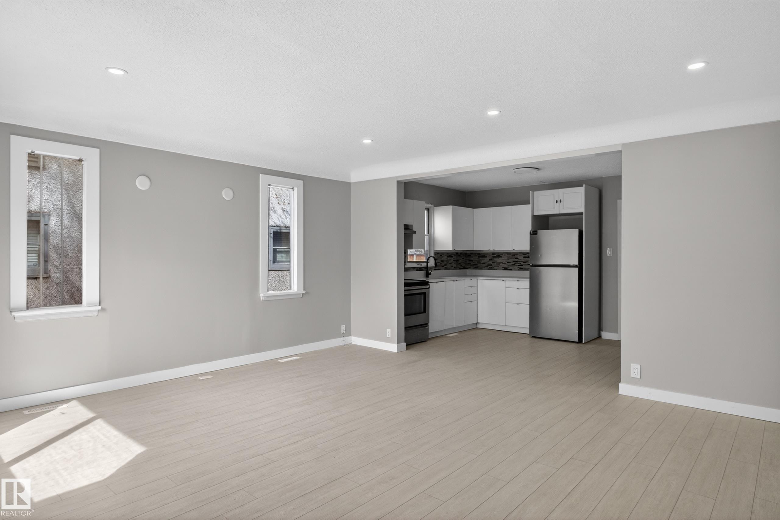 Open-concept living space featuring wood-finish flooring, recessed lighting, and a modern kitchen - 8722 112 Avenue, Edmonton, AB - Indoor Photo Showing Kitchen