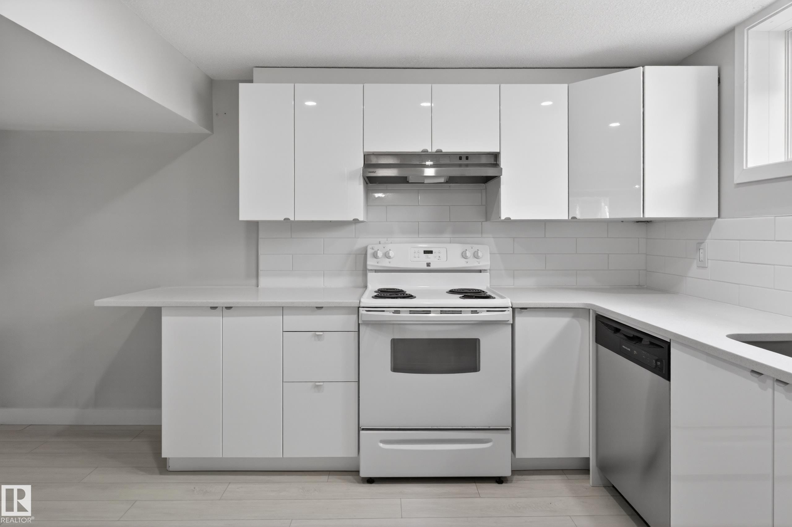 Contemporary kitchen featuring white flat-panel cabinetry, a white subway tile backsplash, and light-toned wood-finish flooring - 8722 112 Avenue, Edmonton, AB - Indoor Photo Showing Kitchen