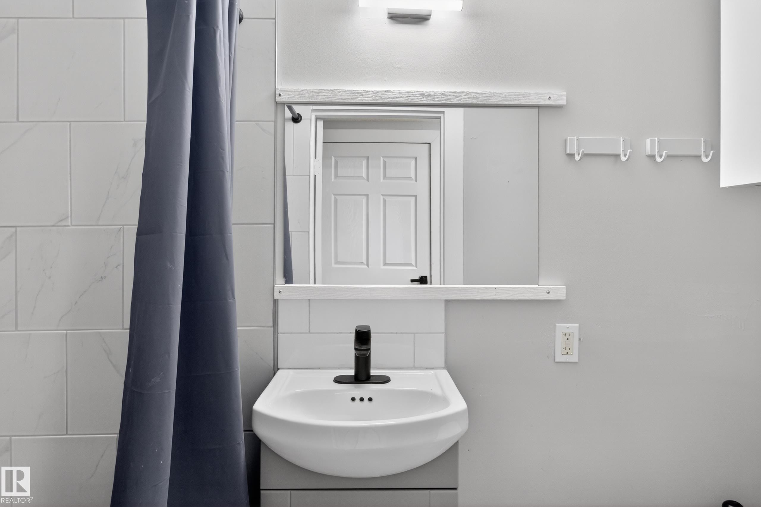 Wall-mounted pedestal sink with a matte black faucet - 8722 112 Avenue, Edmonton, AB - Indoor Photo Showing Bathroom