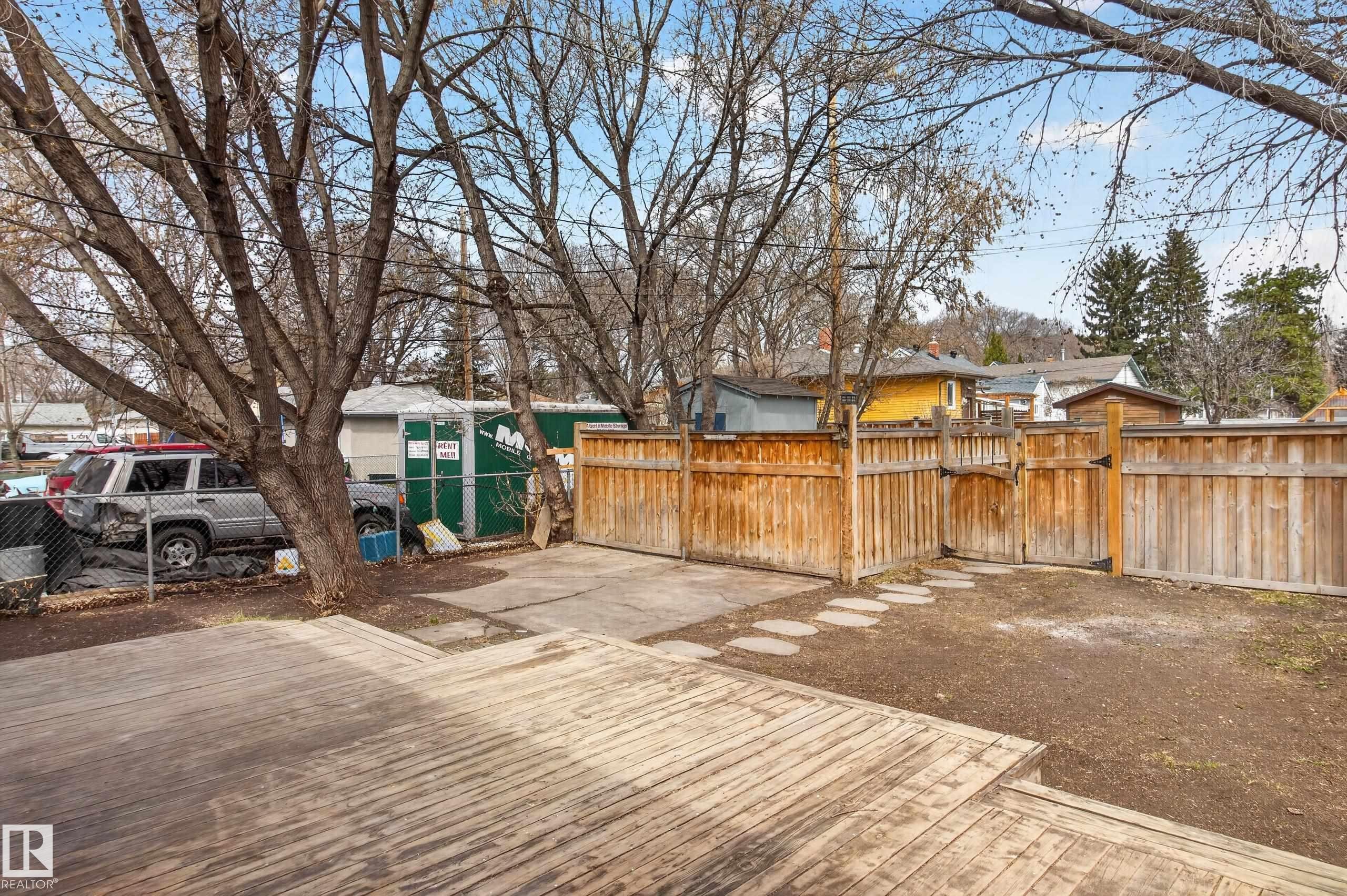 Wood-finish deck with multiple levels, featuring a private yard with wood fencing and stepping stones - 8722 112 Avenue, Edmonton, AB - Outdoor
