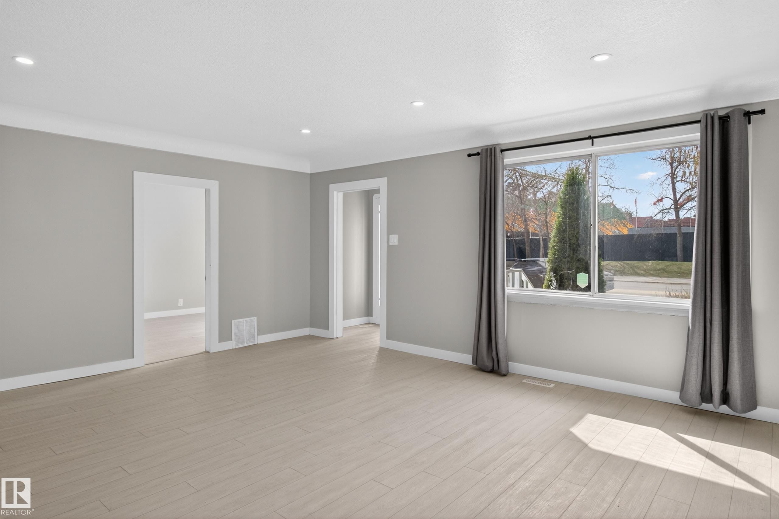 Spacious interior featuring light wood-finish flooring, neutral gray walls, and white trim - 8722 112 Avenue, Edmonton, AB - Indoor Photo Showing Other Room