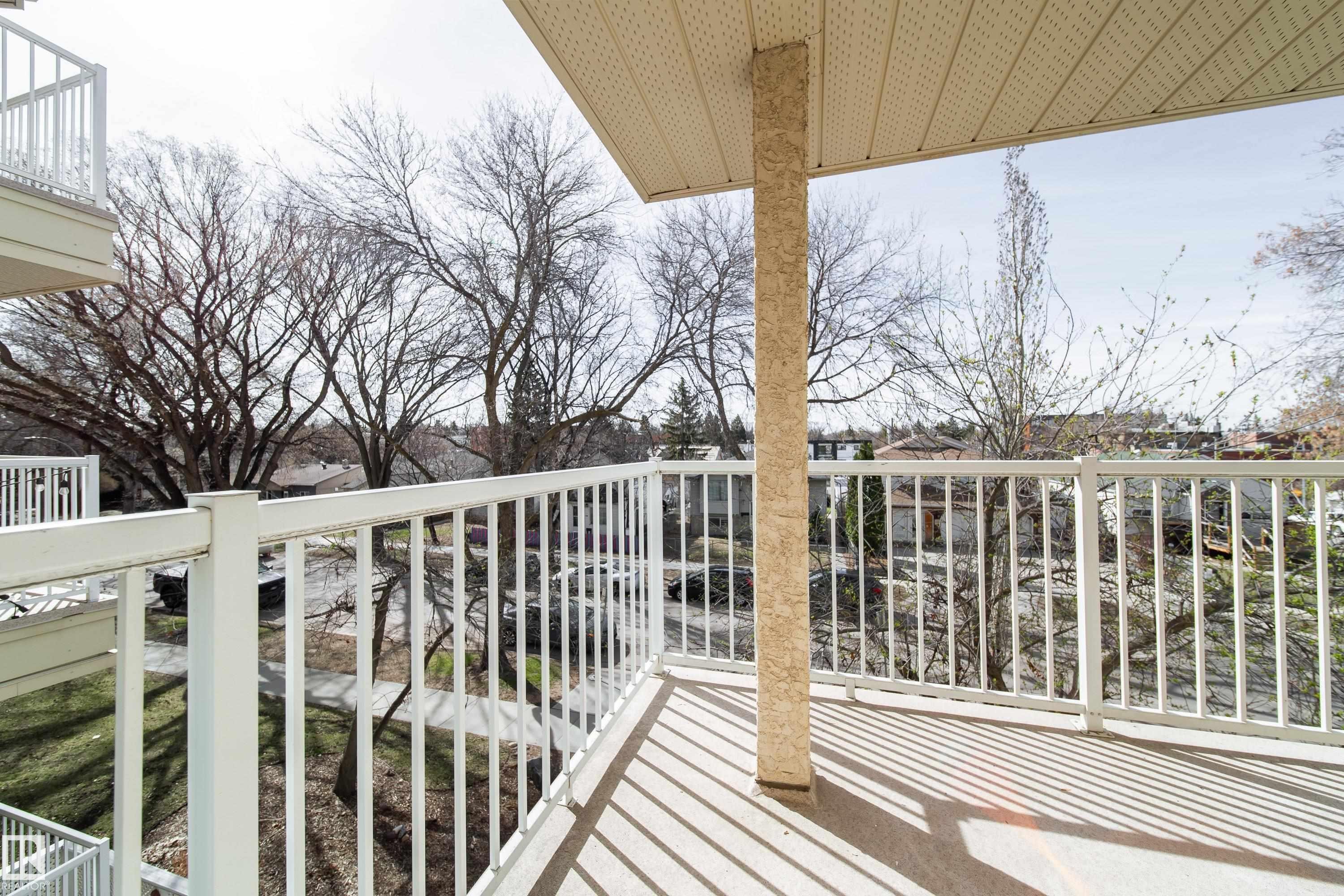 Spacious balcony featuring white metal railings, a textured support column, and an acoustic panel ceiling - 302 9138 83 Avenue, Edmonton, AB - Outdoor With Balcony With Exterior