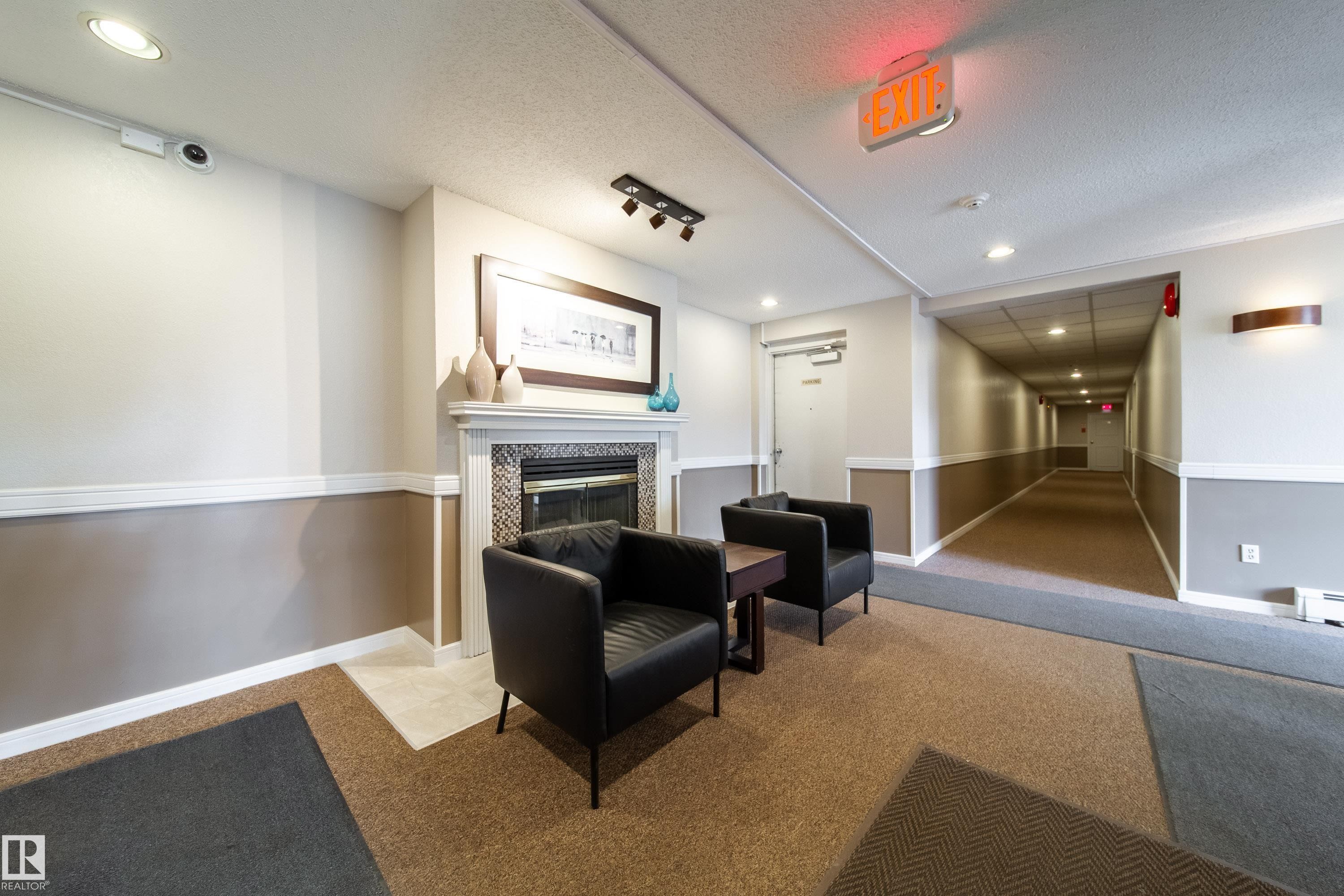 Lobby area featuring a decorative fireplace with a tile surround and white mantel - 302 9138 83 Avenue, Edmonton, AB - Indoor With Fireplace
