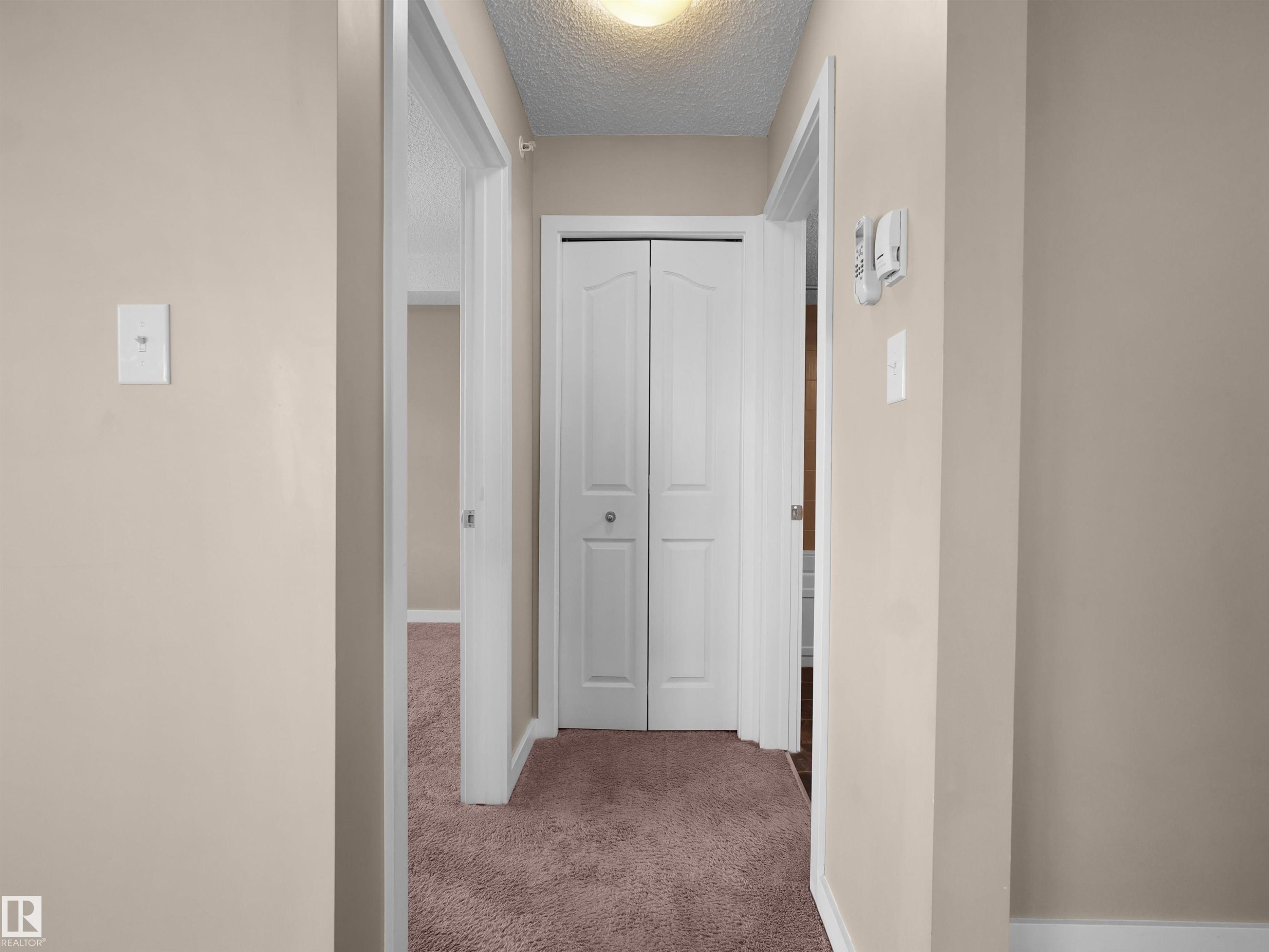 Hallway featuring neutral-toned walls, white trim, and textured carpeting - 417 1060 Mcconachie Boulevard, Edmonton, AB - Indoor Photo Showing Other Room