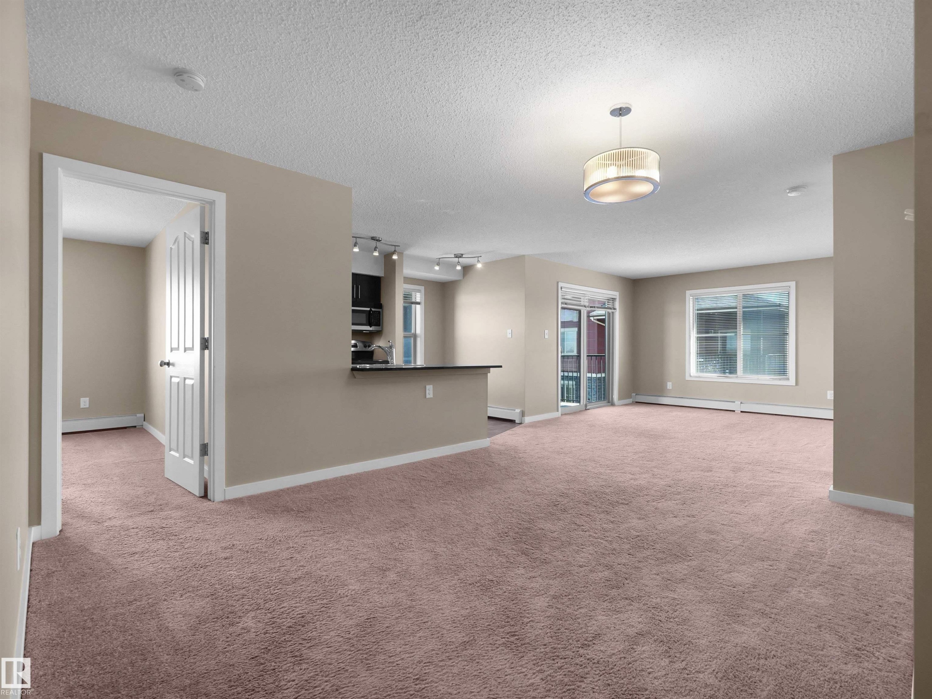 Building exterior featuring a stone facade, multi-story balconies with black railings, a prominent main entrance with glass doors, and a concrete pathway - 417 1060 Mcconachie Boulevard, Edmonton, AB - Outdoor With Balcony