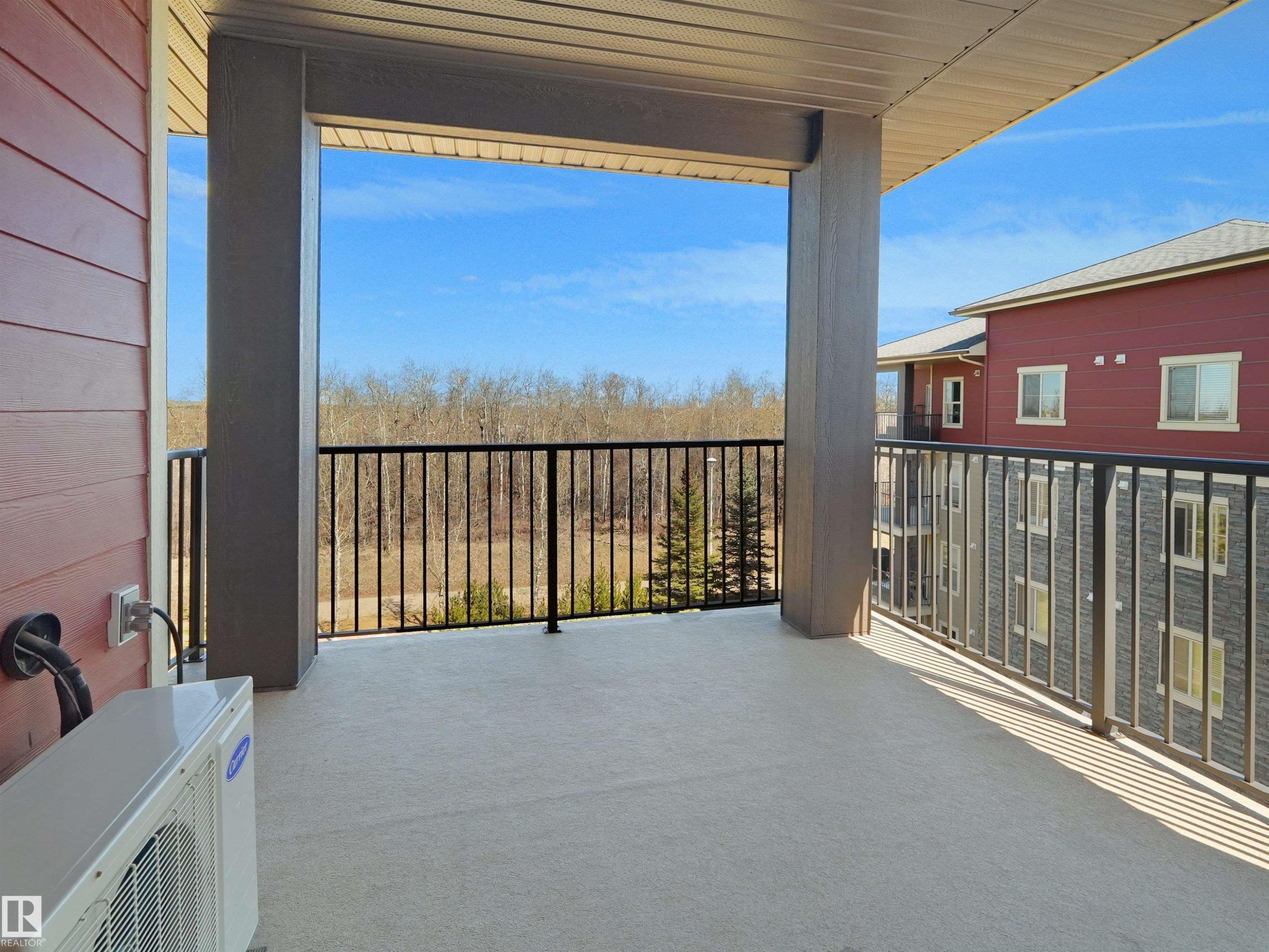 Spacious covered balcony with a concrete surface and black metal railings - 417 1060 Mcconachie Boulevard, Edmonton, AB - Outdoor With Balcony With Exterior