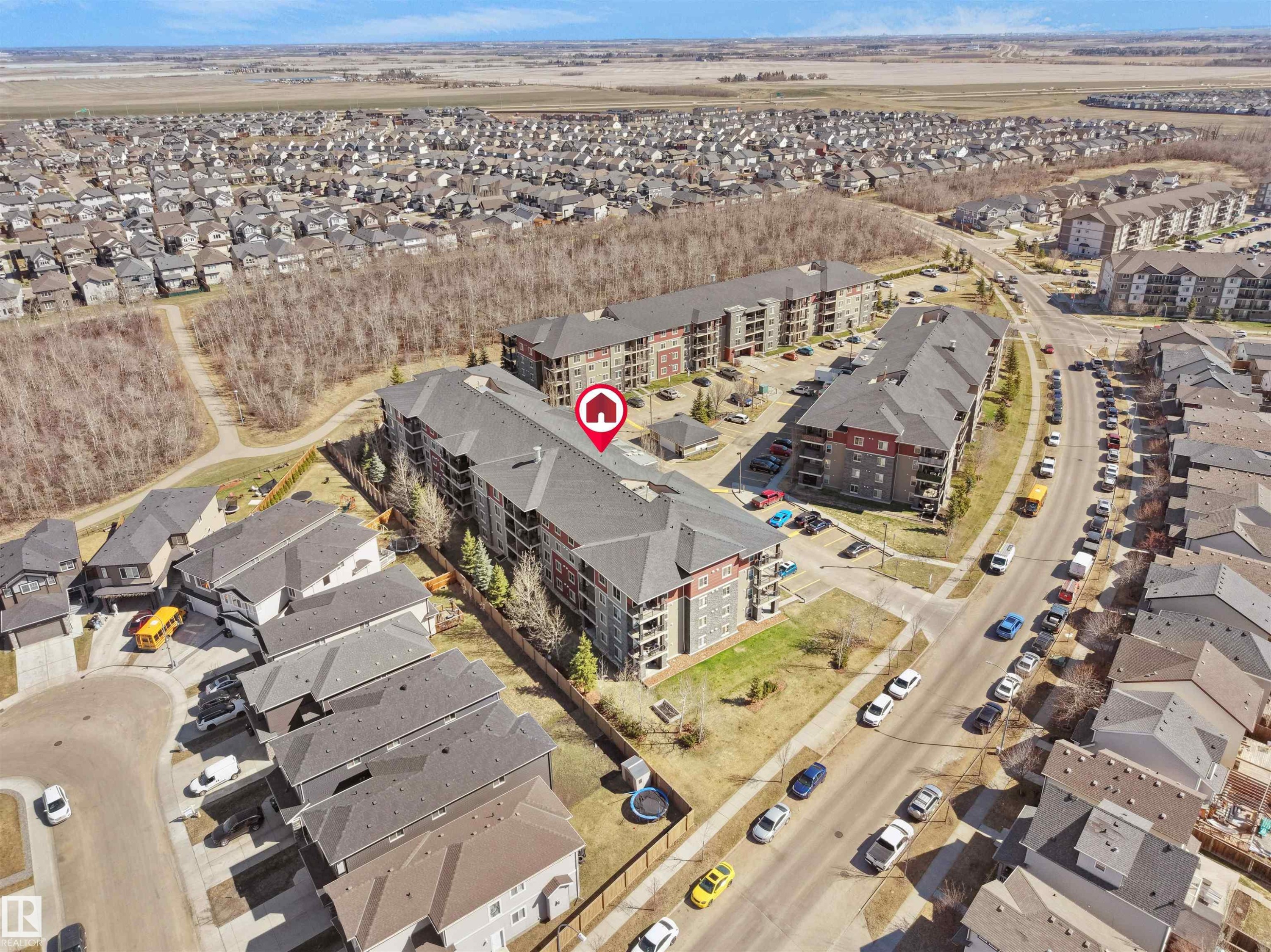 Aerial perspective showcasing a multi-story residential building with grey and red-brown exterior paneling and dark roofing - 417 1060 Mcconachie Boulevard, Edmonton, AB - Outdoor With View