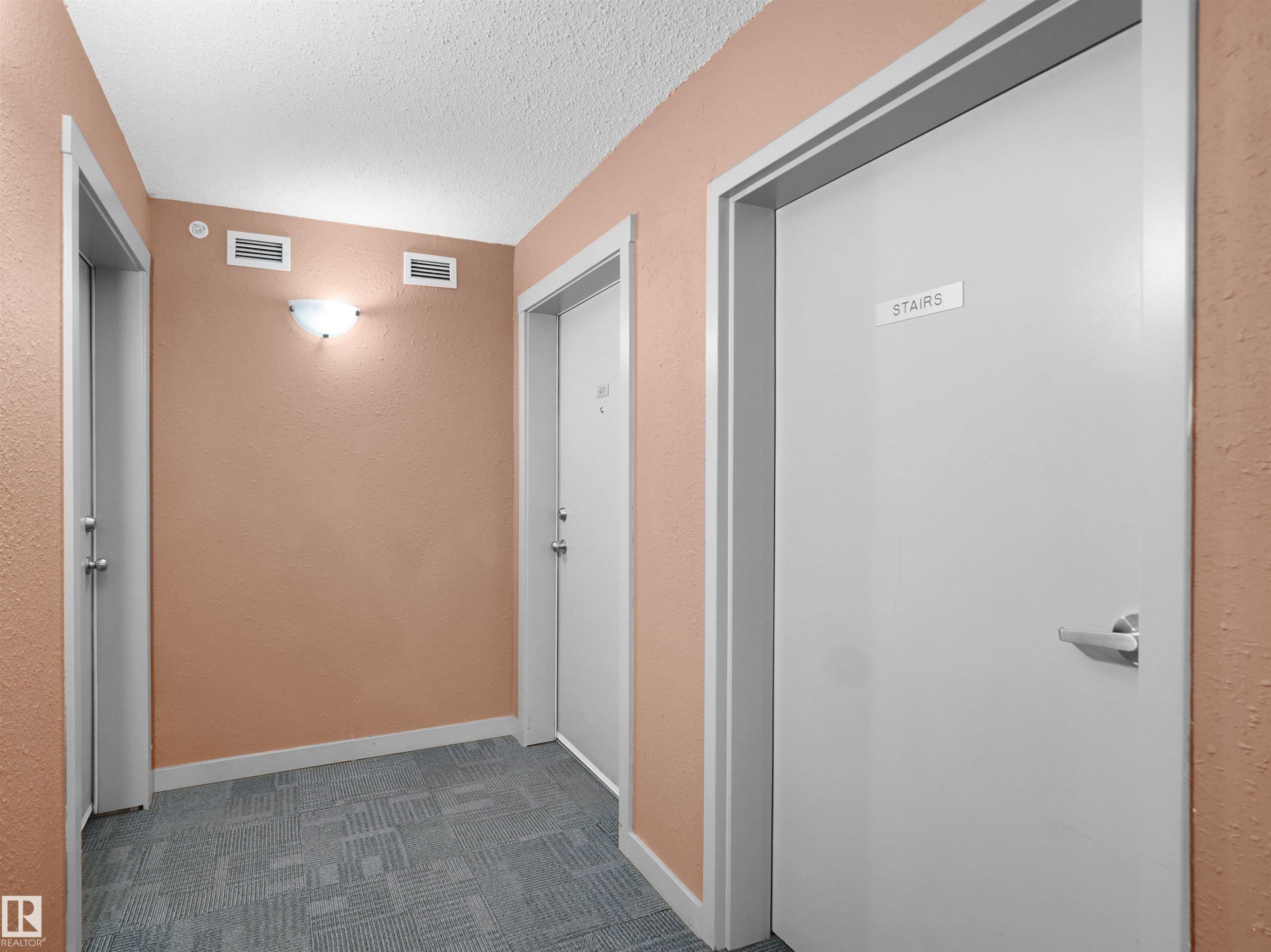 Hallway featuring textured peach-toned walls and a patterned carpet floor - 417 1060 Mcconachie Boulevard, Edmonton, AB - Indoor Photo Showing Other Room