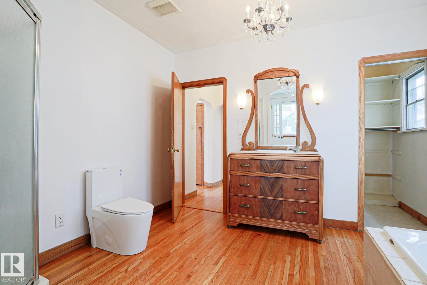 Hardwood flooring extends throughout this space featuring a modern toilet, a shower enclosure, and a built-in closet with shelving - 9611 81 Avenue, Edmonton, AB - Indoor Photo Showing Bathroom