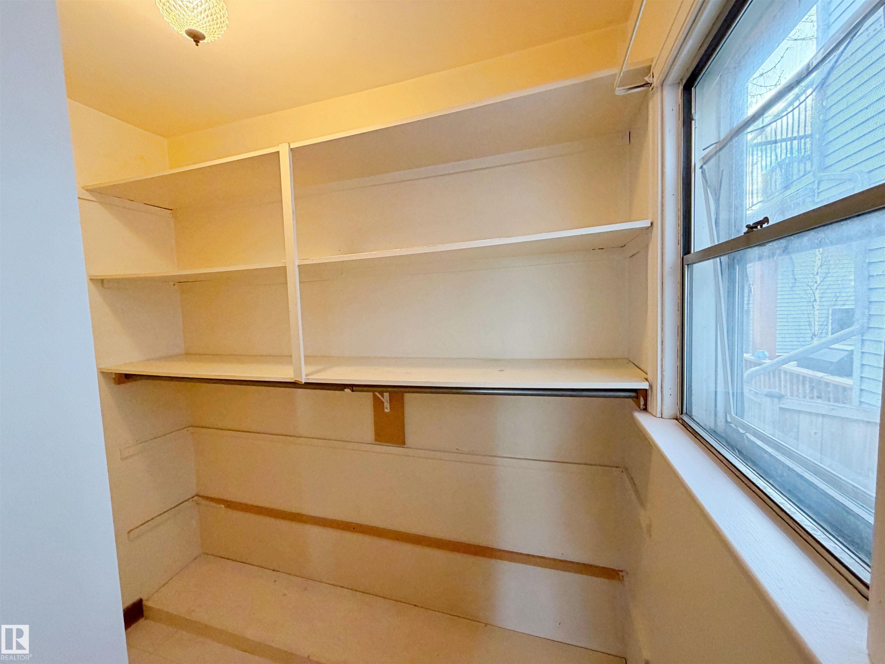 Built-in shelving with multiple levels, integrated clothes rod, and a window providing natural light - 9611 81 Avenue, Edmonton, AB - Indoor With Storage