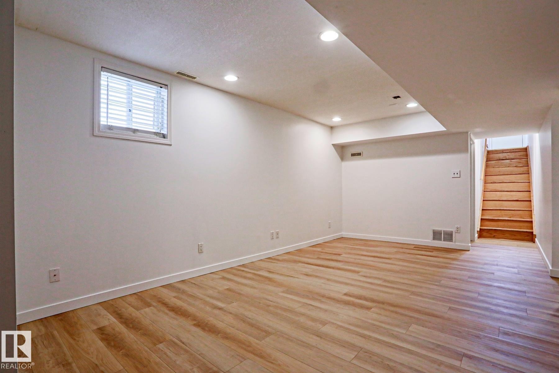 Spacious room featuring wood-finish flooring, recessed lighting, and a window with blinds - 9611 81 Avenue, Edmonton, AB - Indoor Photo Showing Other Room