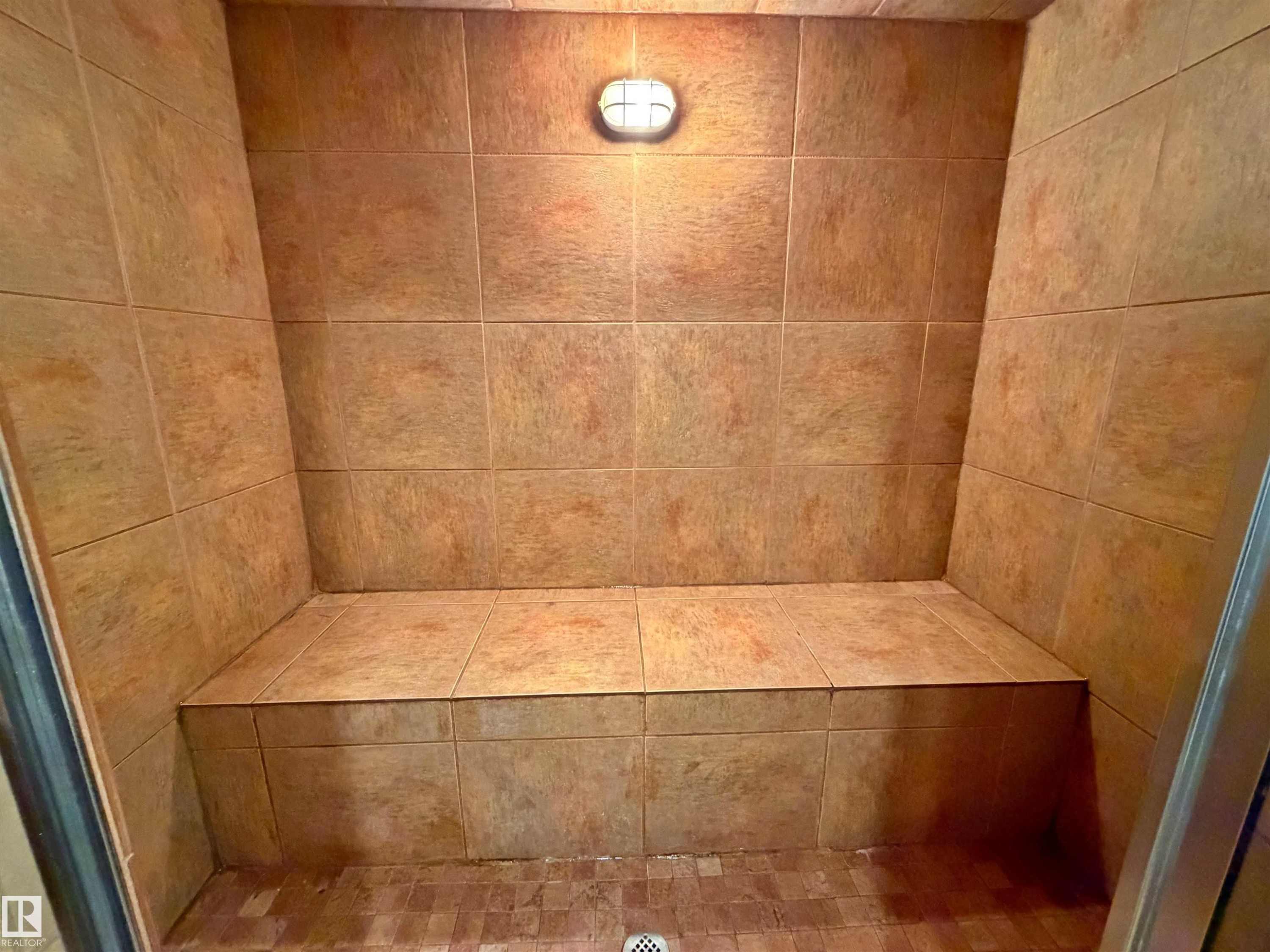 Tiled shower enclosure featuring a built-in bench, recessed lighting, and textured floor tiles - 9611 81 Avenue, Edmonton, AB - Indoor Photo Showing Bathroom