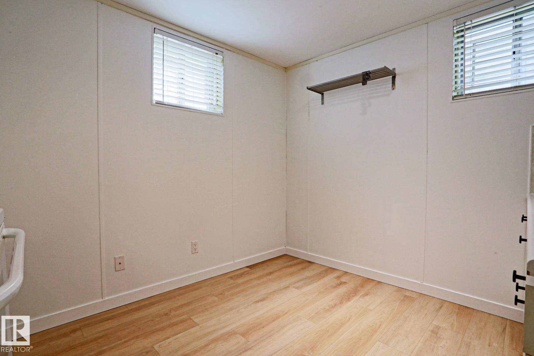Room featuring wood-finish flooring, two windows with blinds, and white paneling walls - 9611 81 Avenue, Edmonton, AB - Indoor Photo Showing Other Room
