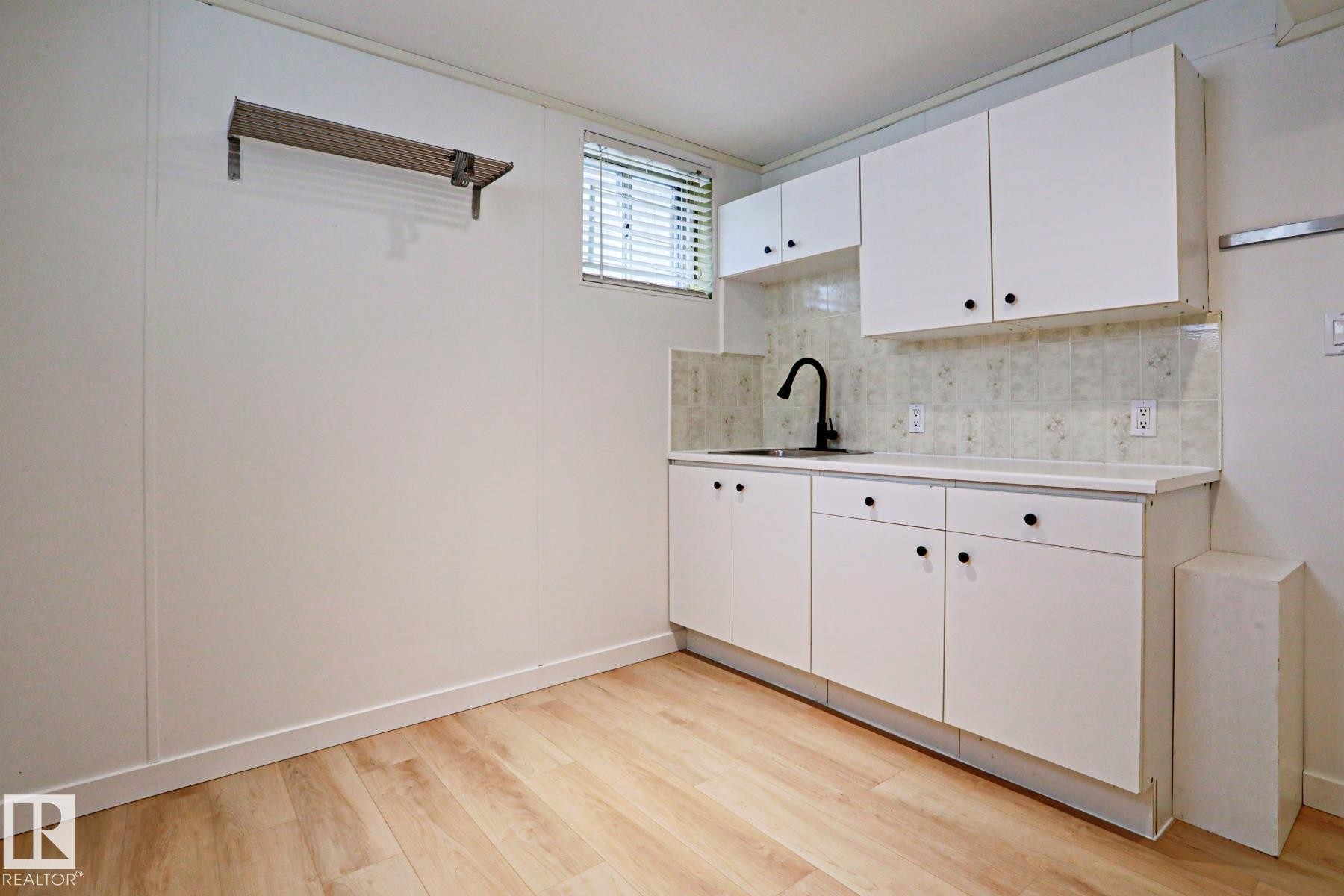 Utility area featuring light wood-finish flooring, white panel walls, and a window with blinds - 9611 81 Avenue, Edmonton, AB - Indoor