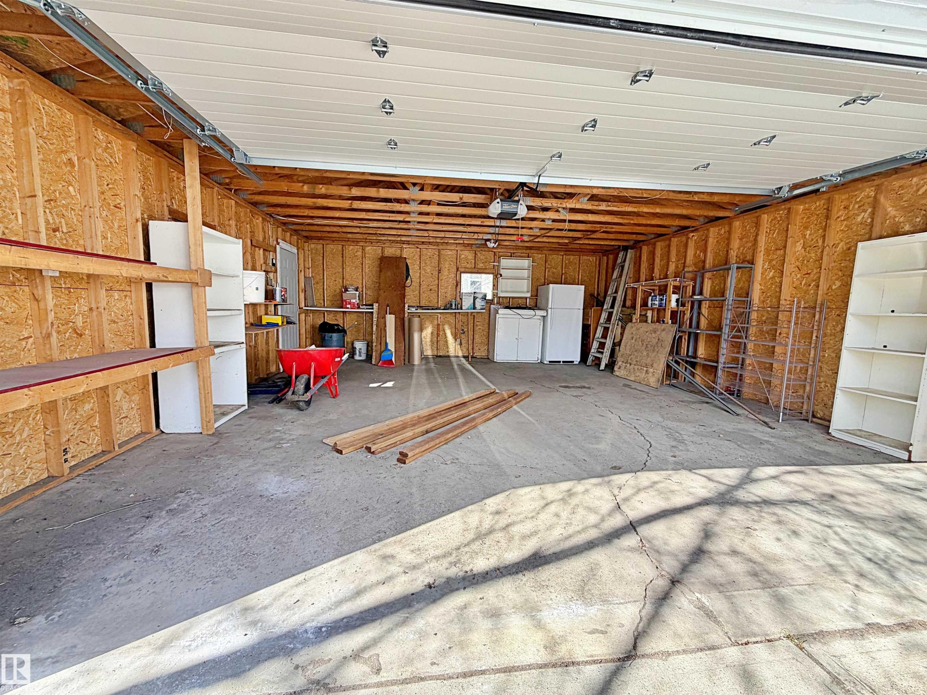 Spacious garage with exposed wood-finish walls, a concrete floor, and an overhead garage door - 9611 81 Avenue, Edmonton, AB - Indoor Photo Showing Garage