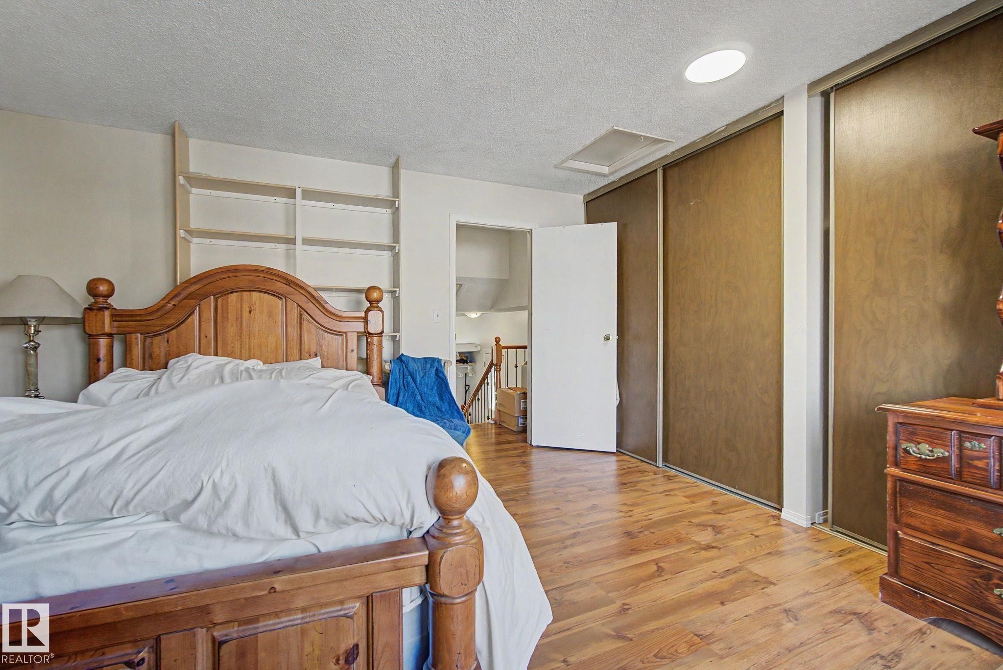 Bedroom featuring wood-finish flooring, built-in shelving, a recessed ceiling light, and sliding closet doors - 4106 38 Street, Edmonton, AB - Indoor Photo Showing Bedroom