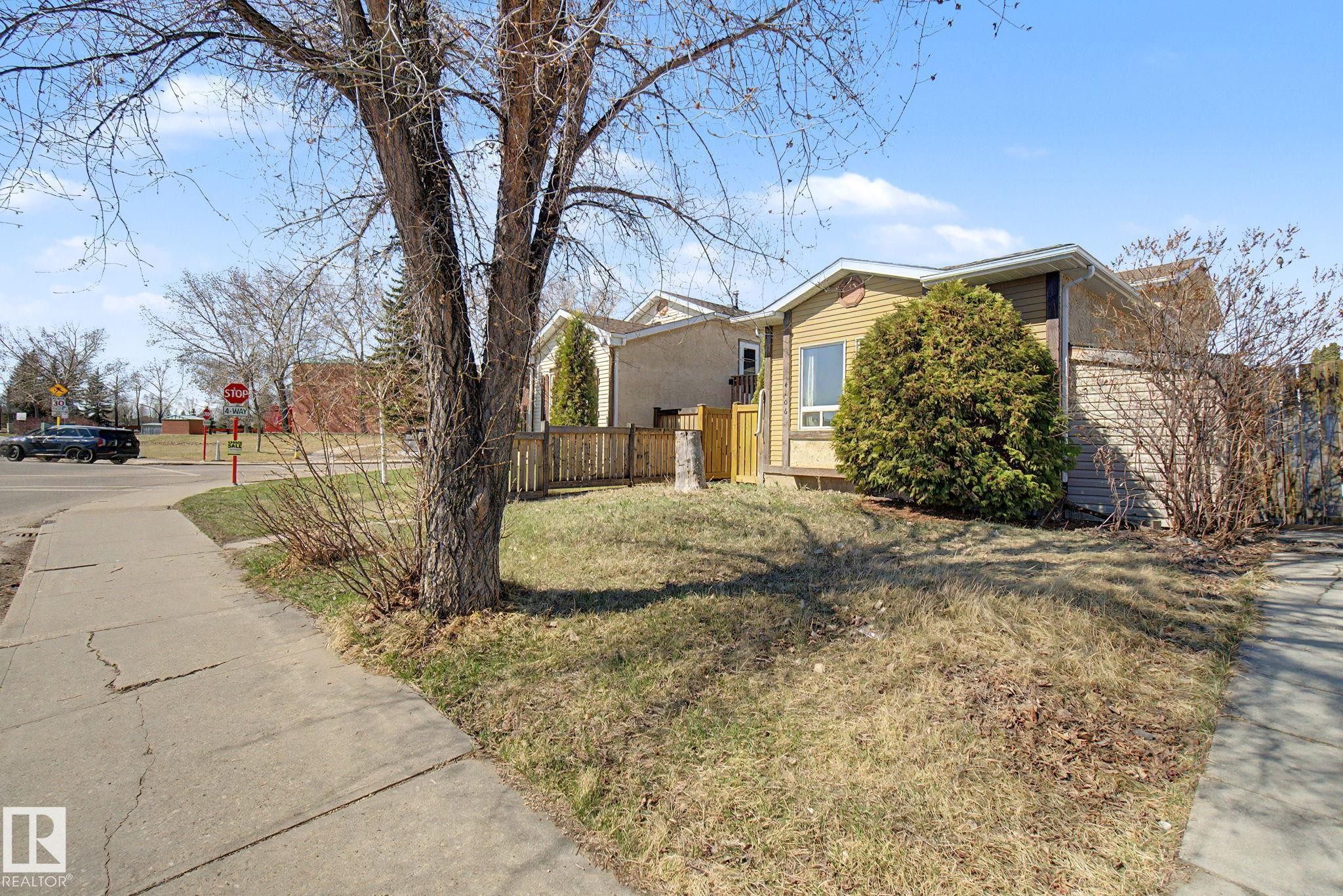 Exterior property featuring yellow siding, a prominent front window, and mature landscaping - 4106 38 Street, Edmonton, AB - Outdoor