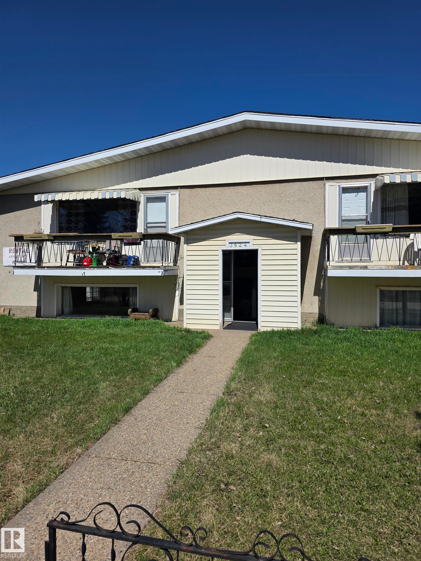 Exterior facade featuring a central entrance, two upper-level balconies with awnings, and an asphalt pathway - 3624 117 Avenue, Edmonton, AB - Outdoor