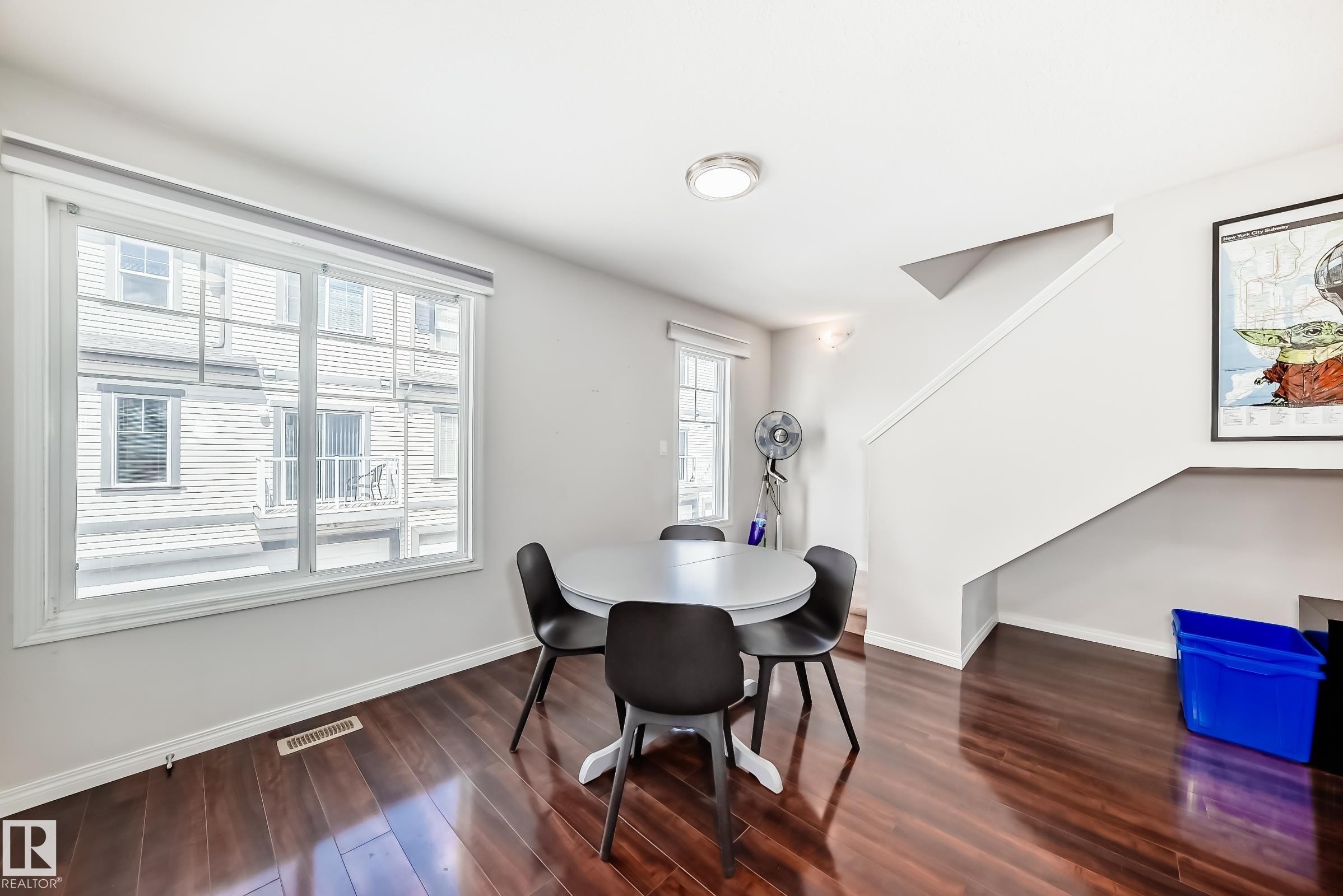 Dining area featuring wood-finish flooring, a large window with white trim, light gray painted walls, and a recessed ceiling light - 45 4850 Terwillegar Common, Edmonton, AB - Indoor Photo Showing Dining Room